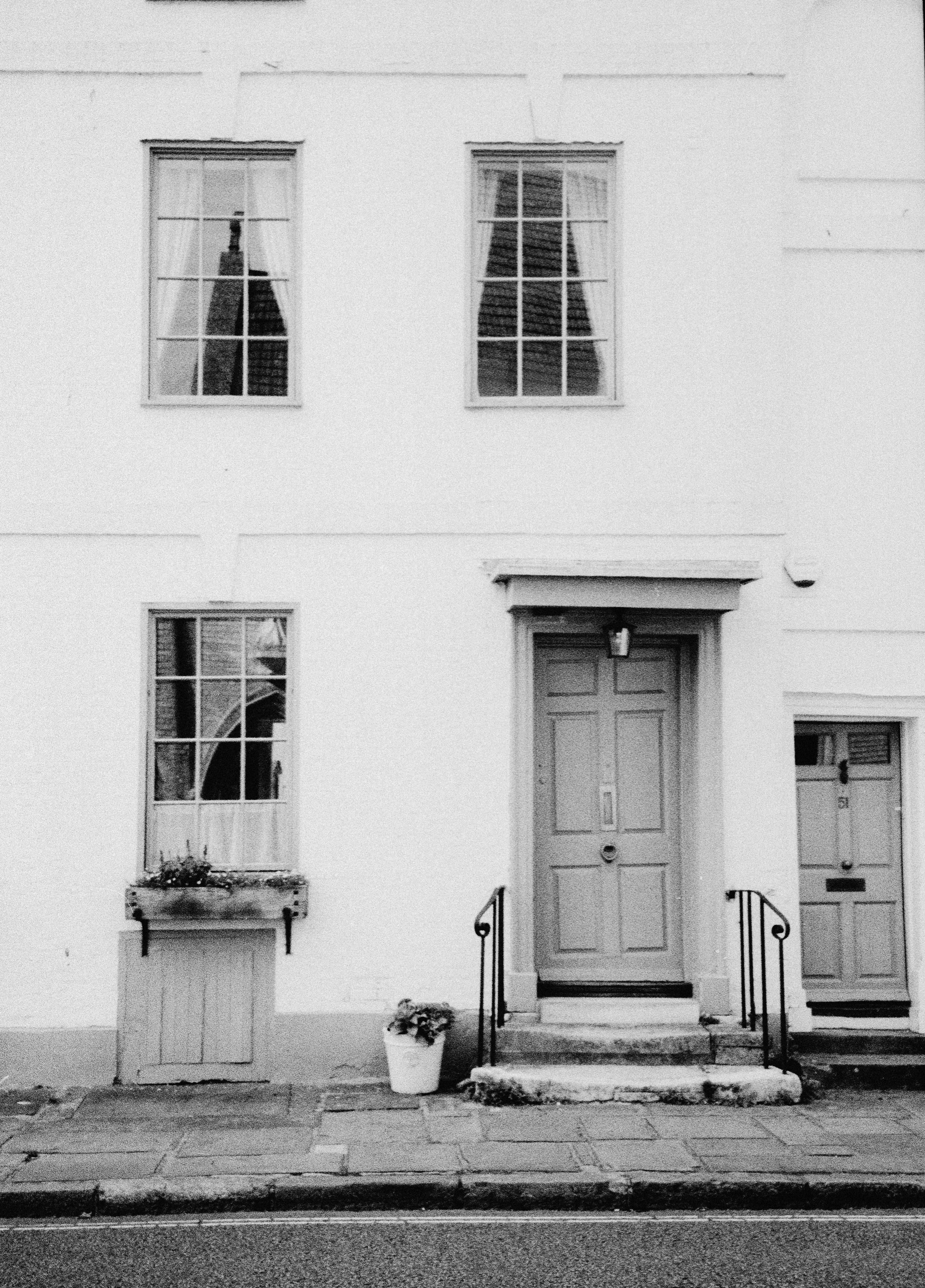 A white building facade with two doors, sash windows, and a flower box