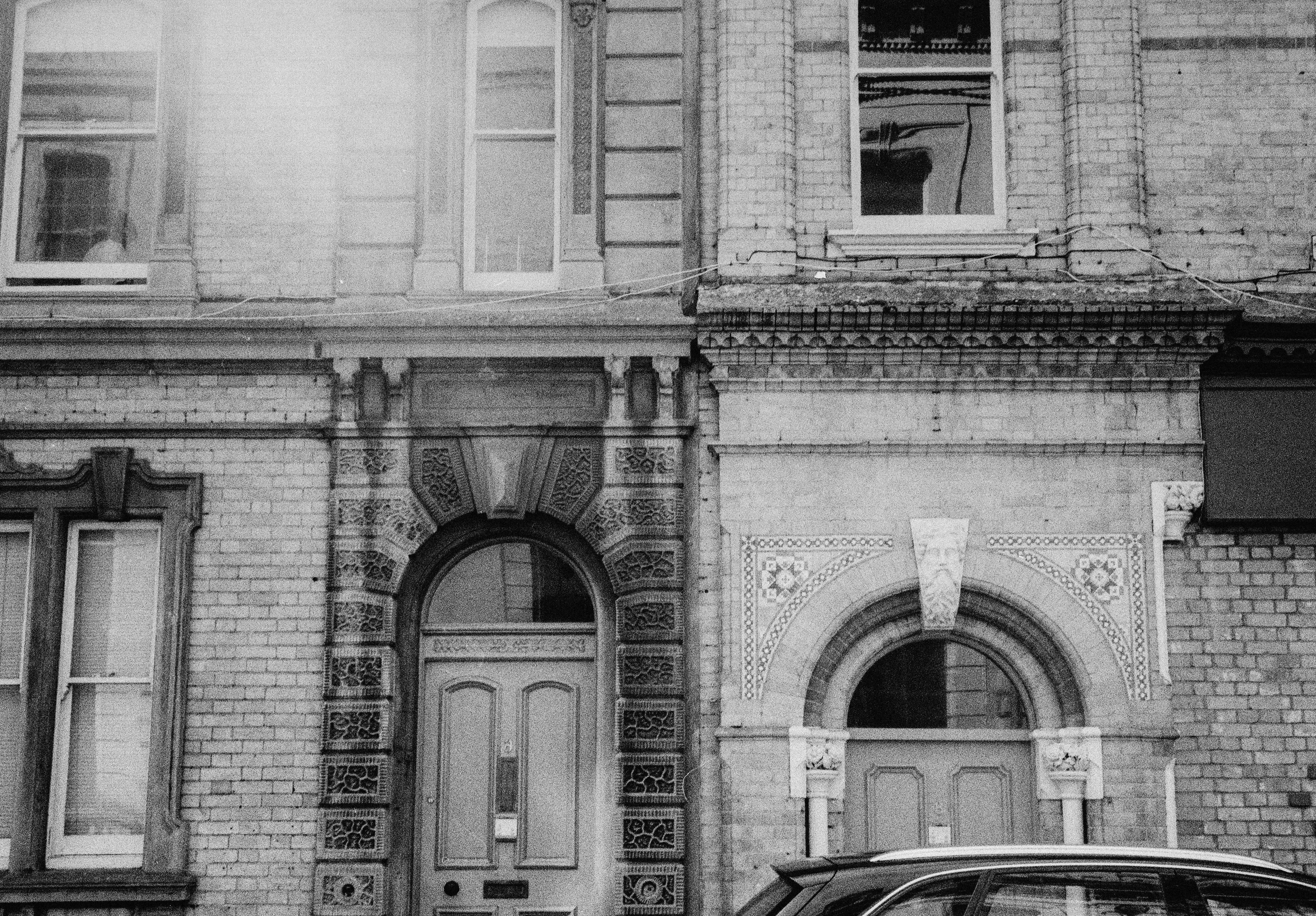 Two brick building facades with arched doorways and windows in black and white