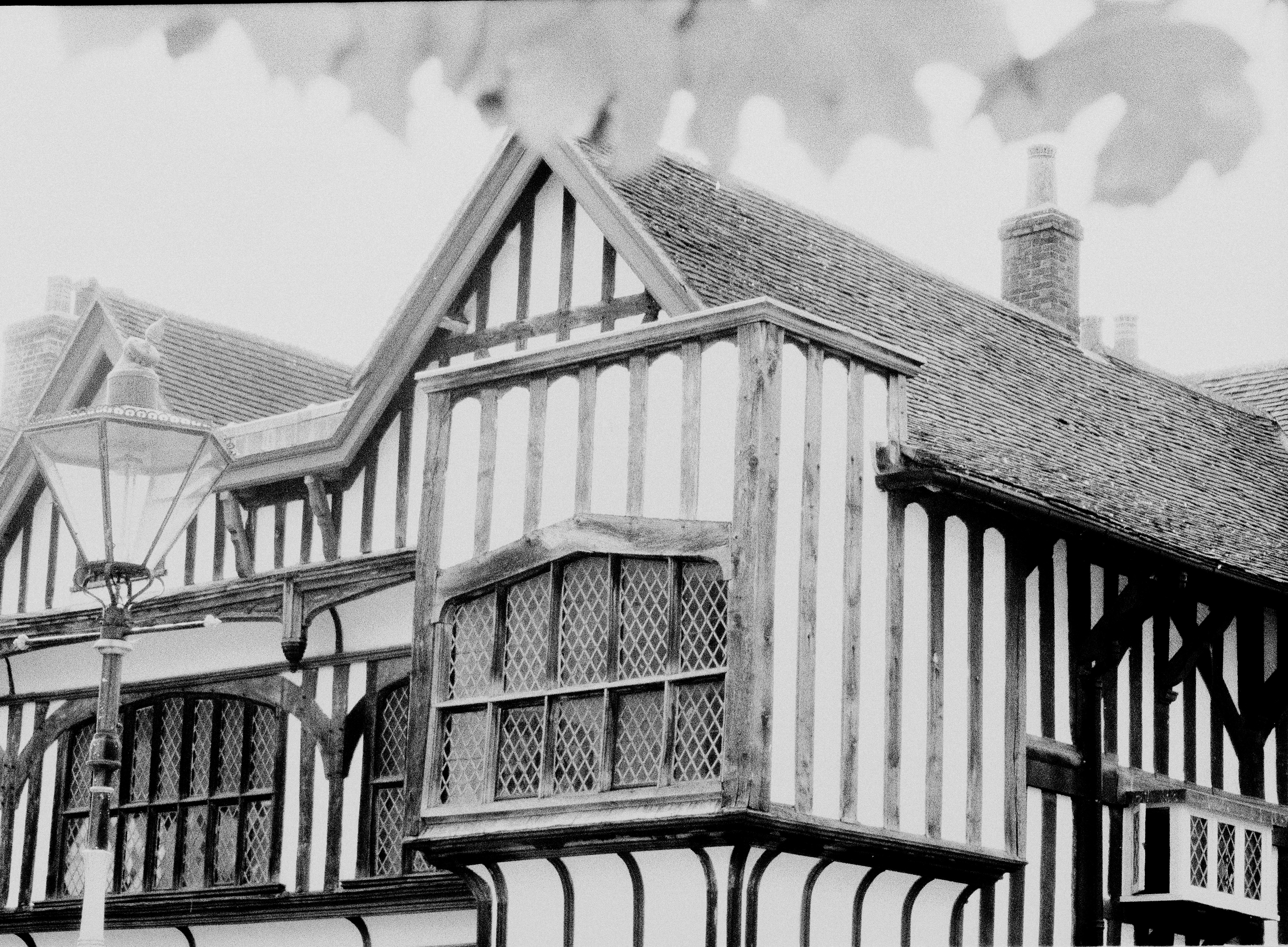A black and white view of a timber-framed building with leaded glass windows