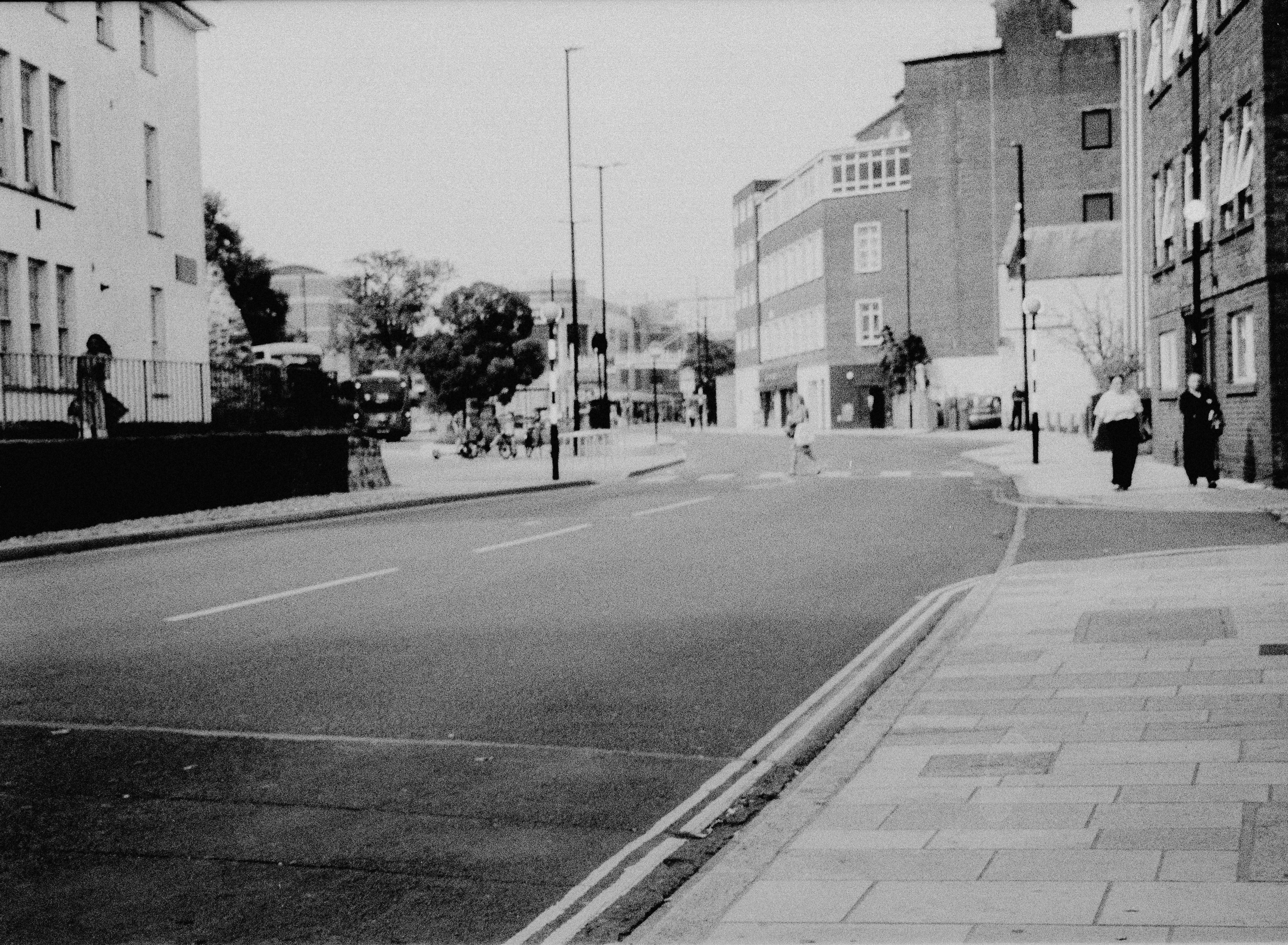 People walking on a quiet city street with brick buildings in black and white