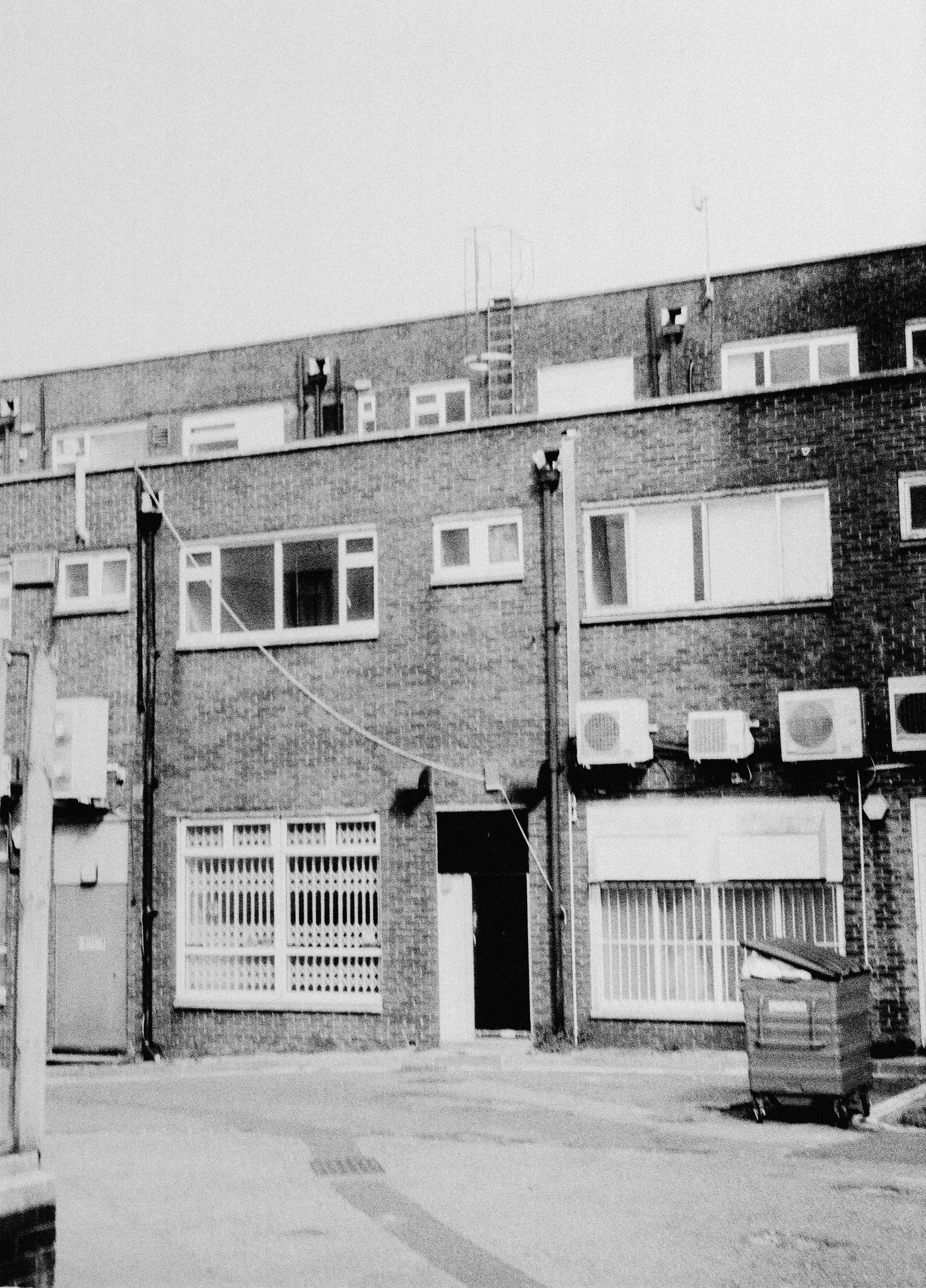A black and white view of a brick apartment building with air conditioning units