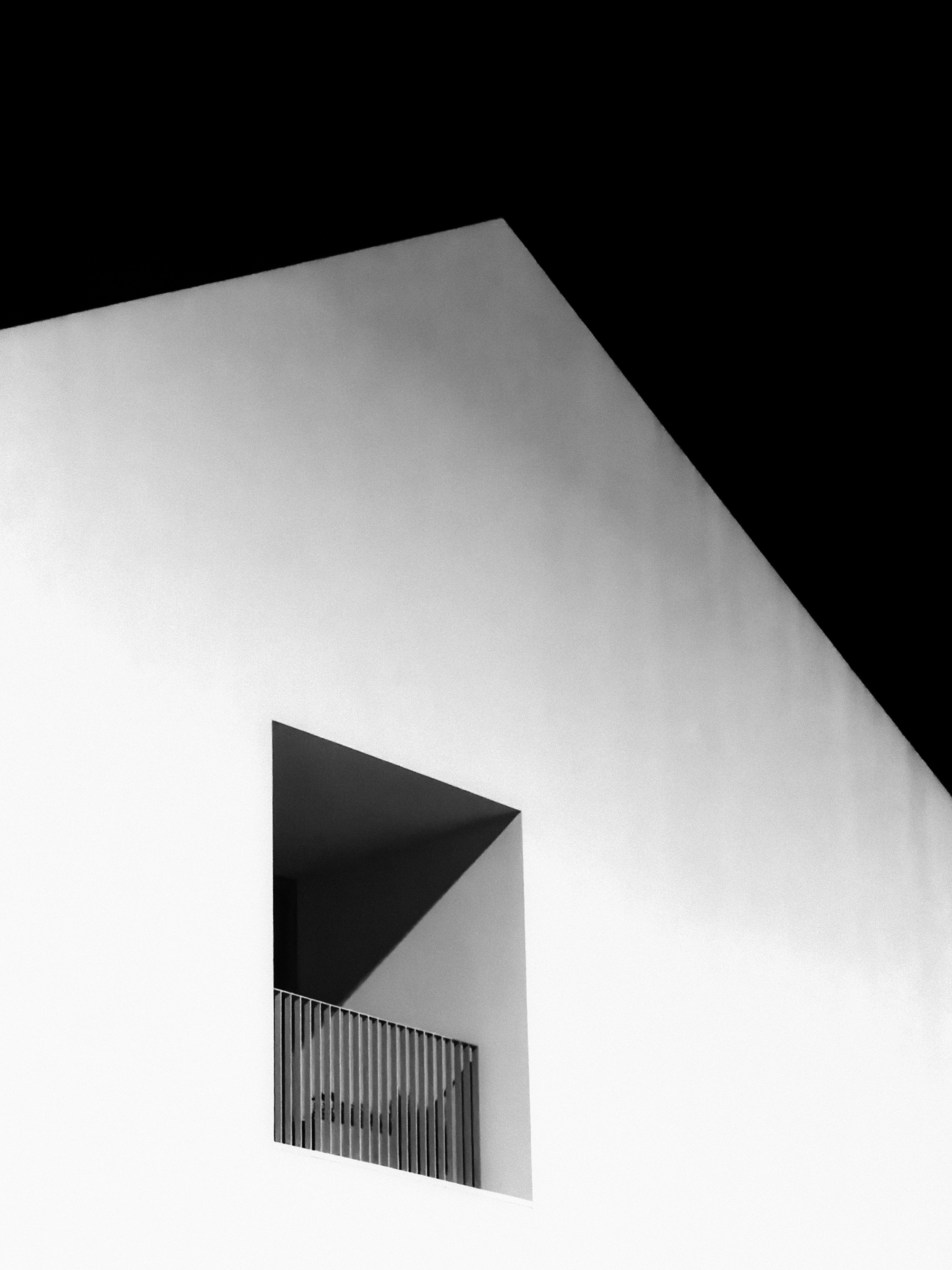A white building corner with a recessed balcony against a black sky