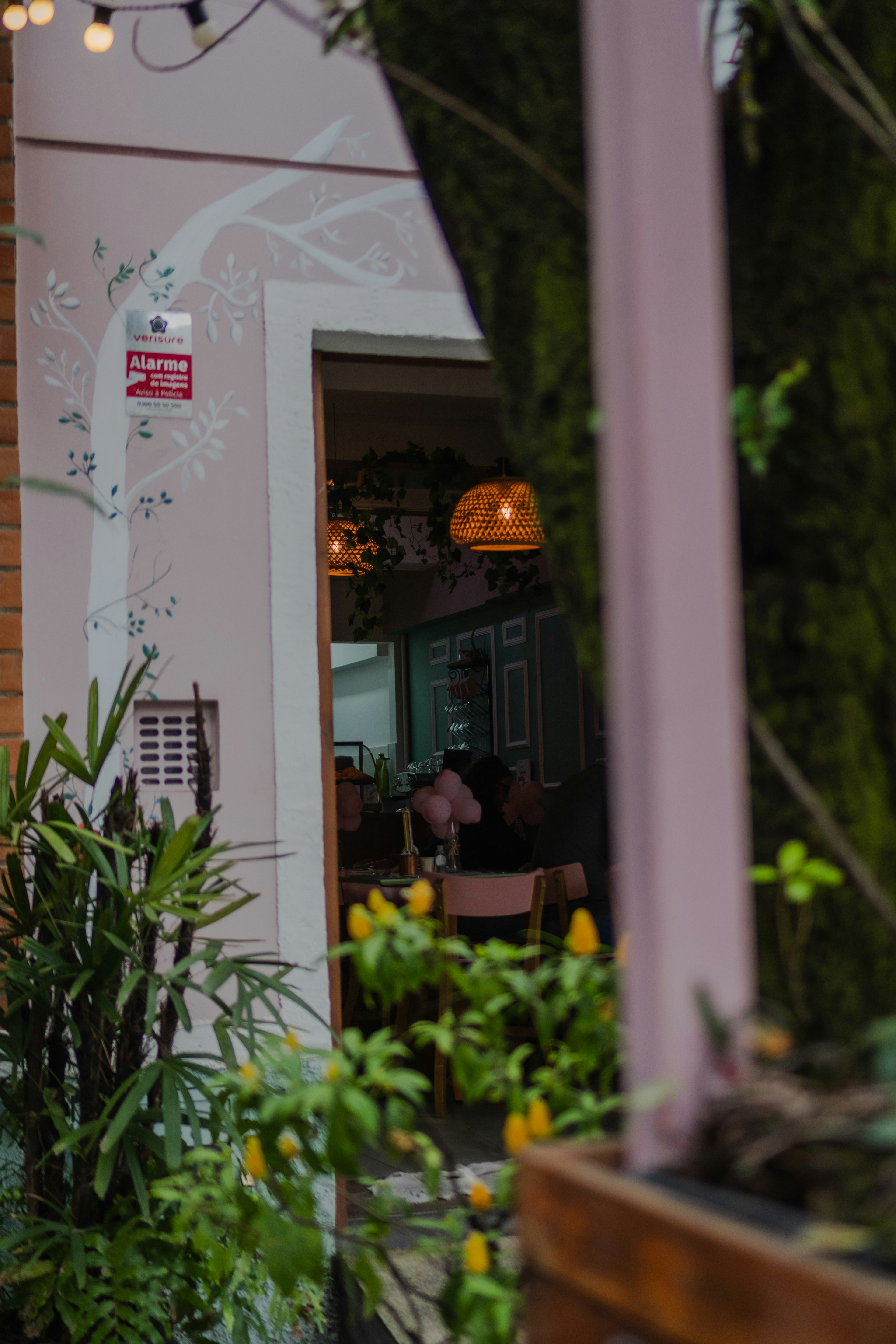 A view through a doorway into a cafe with wicker pendant lights