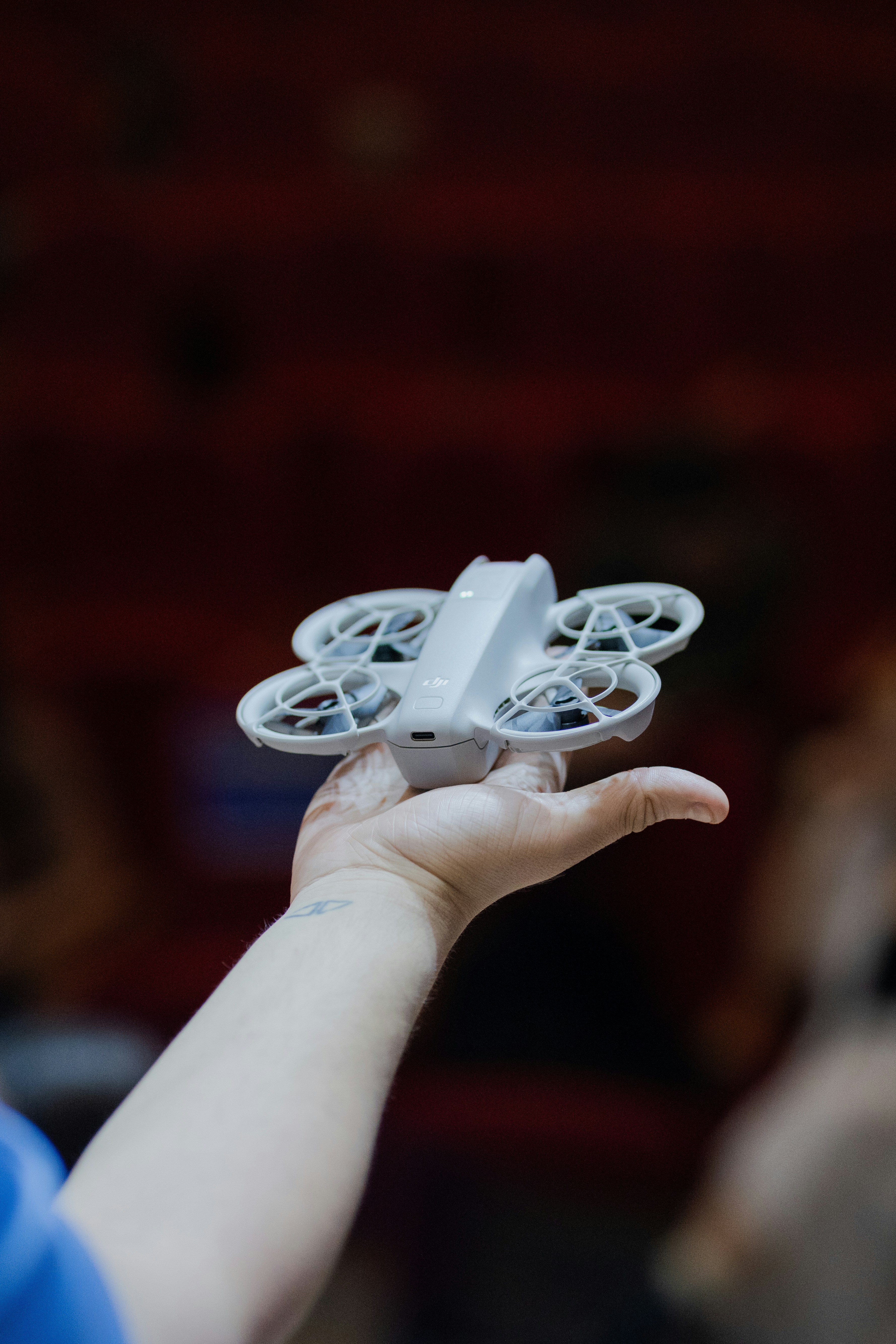 A small grey drone with propeller guards resting on a person's open palm