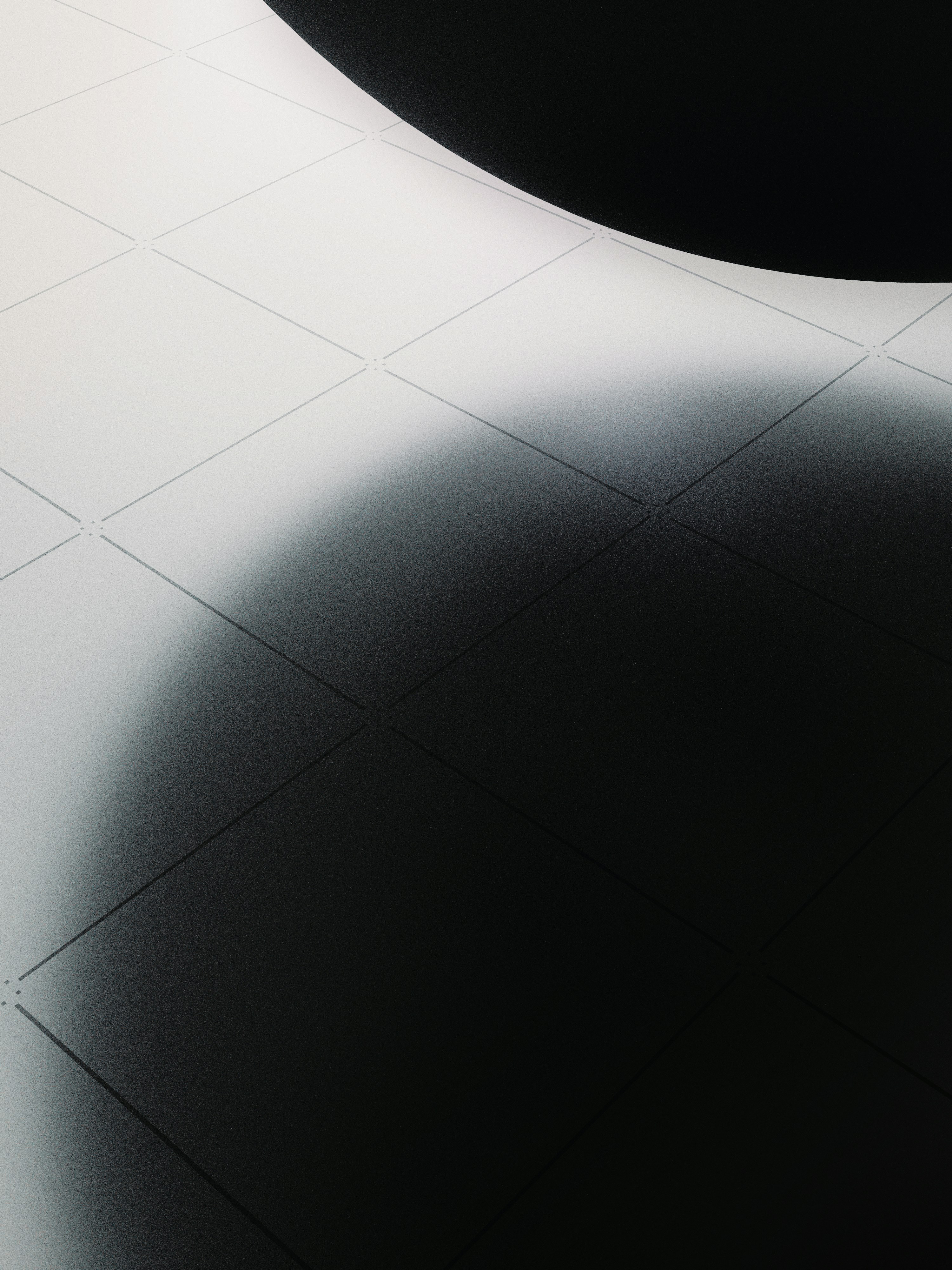 A grid of white tiles partially obscured by a large dark curved shadow