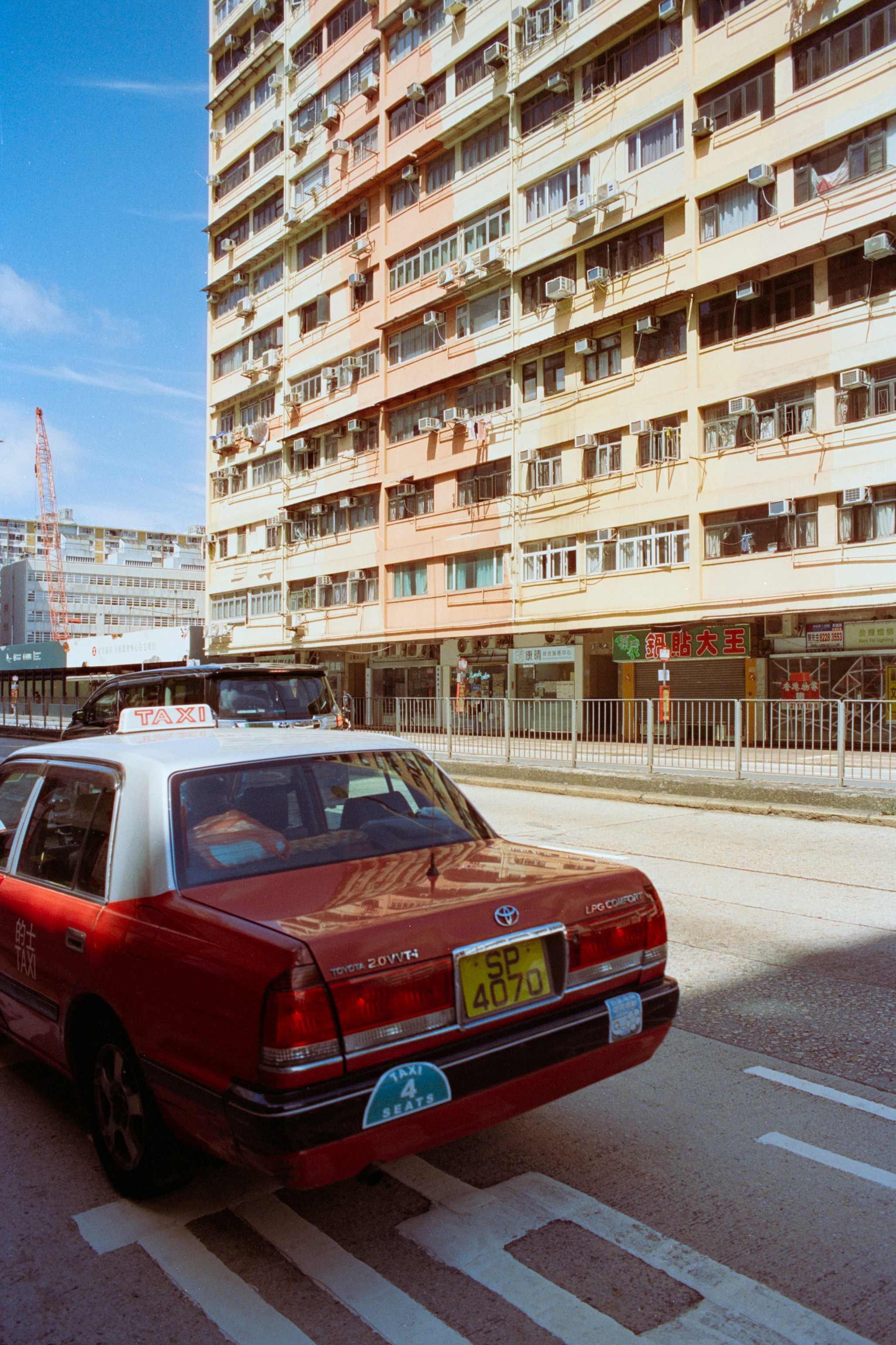 A red and white taxi on a street in front of a tall apartment building