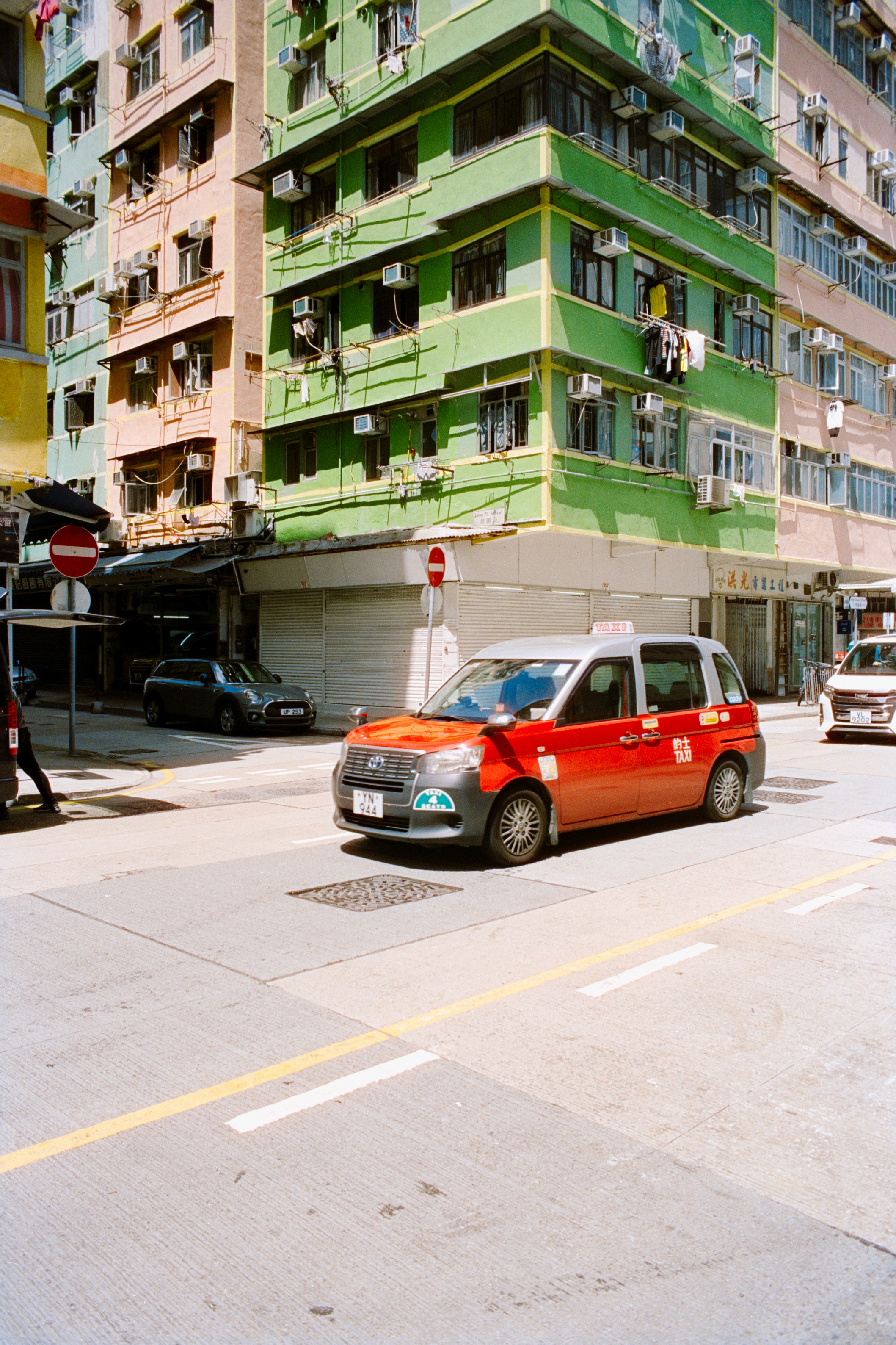 A red and silver taxi driving through a street intersection in Hong Kong