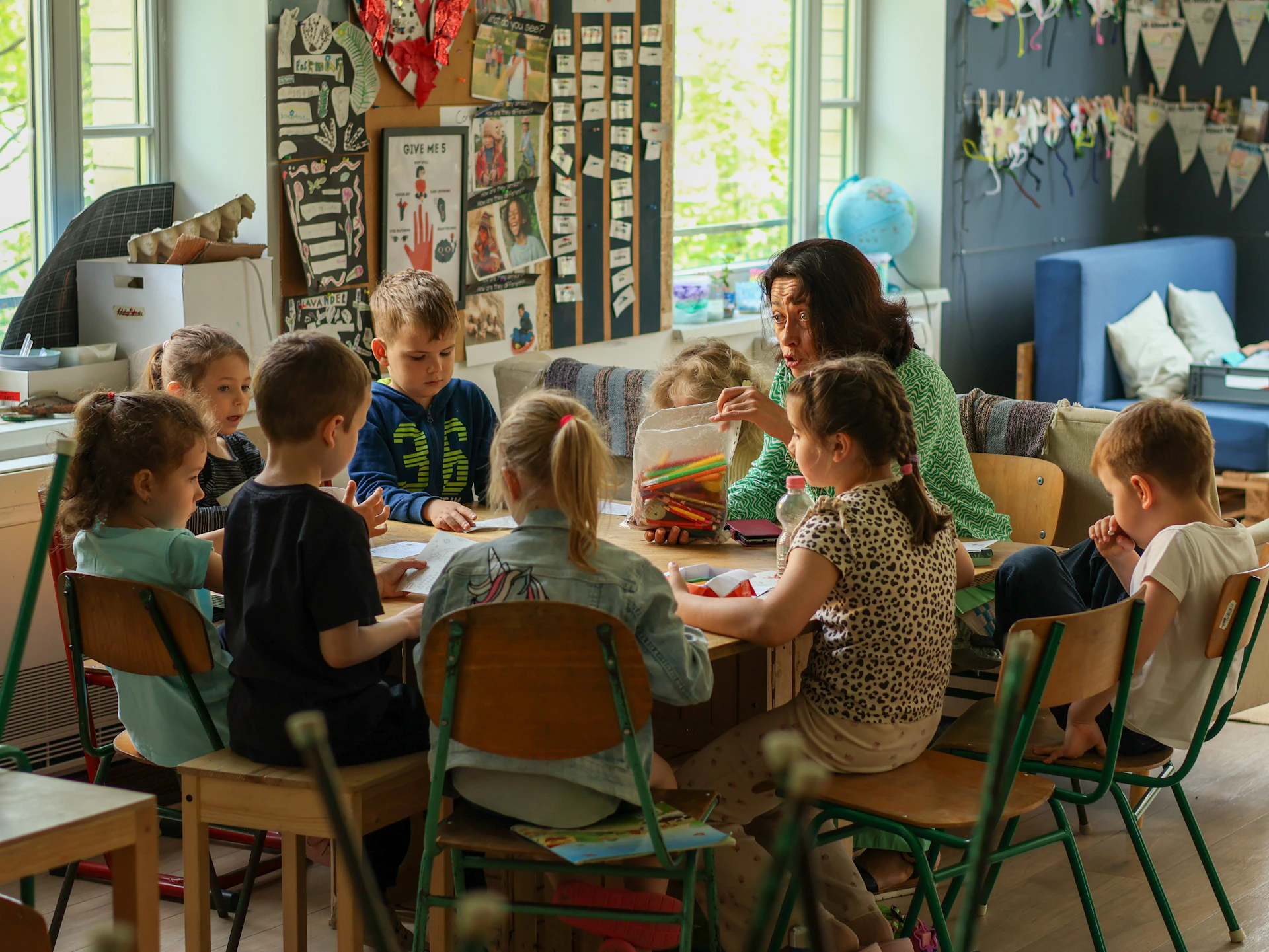 An adult and a group of children sitting at a table in a classroom