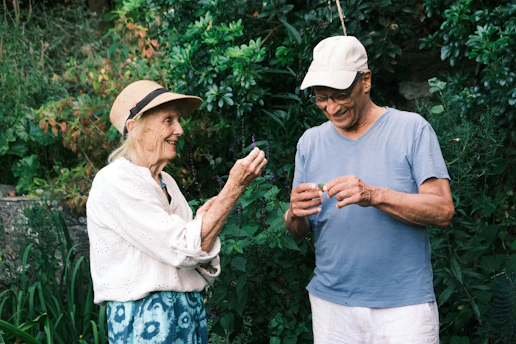 An older woman and man examining small leaves in a lush green garden