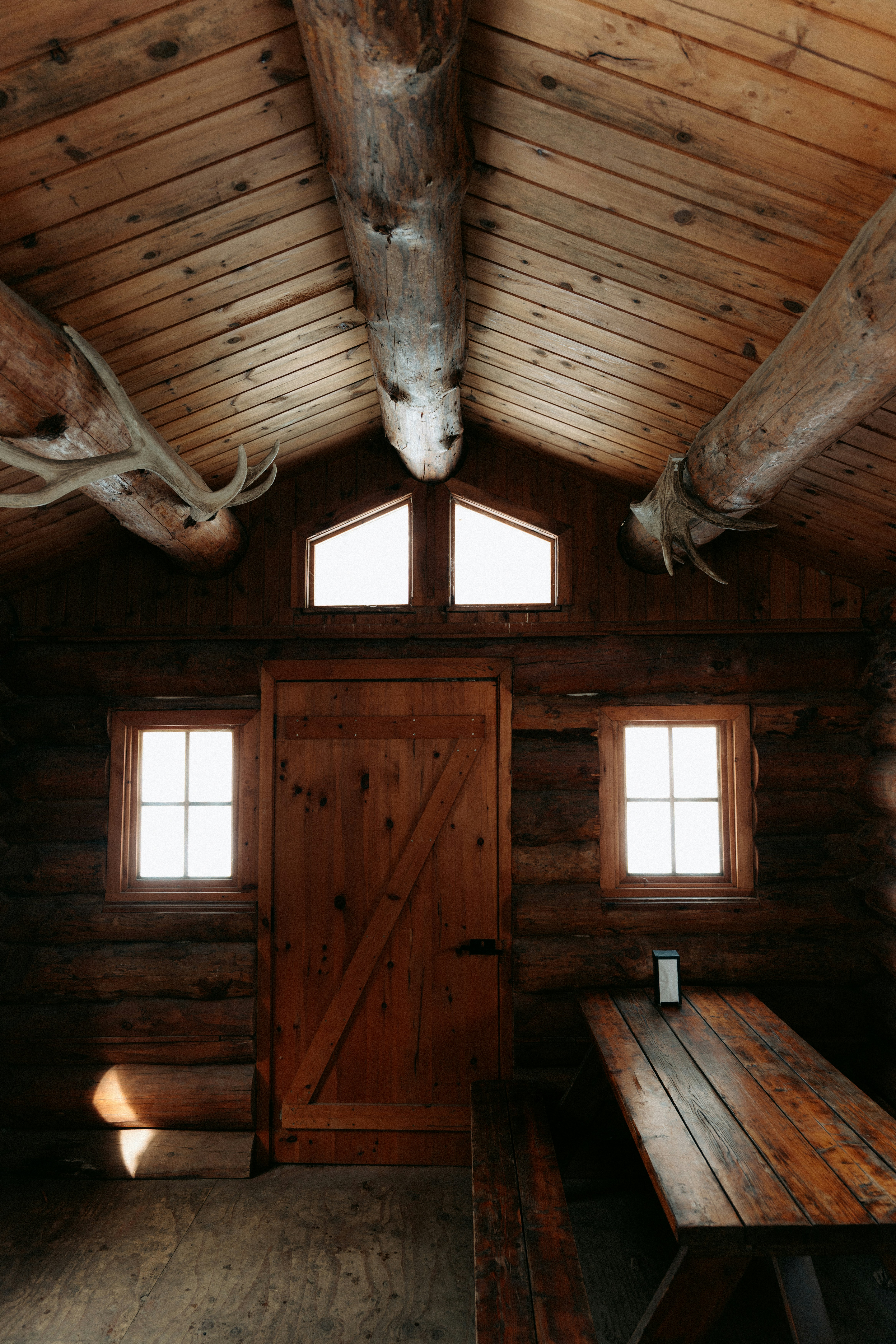 A rustic log cabin interior with antler decor and a wooden table