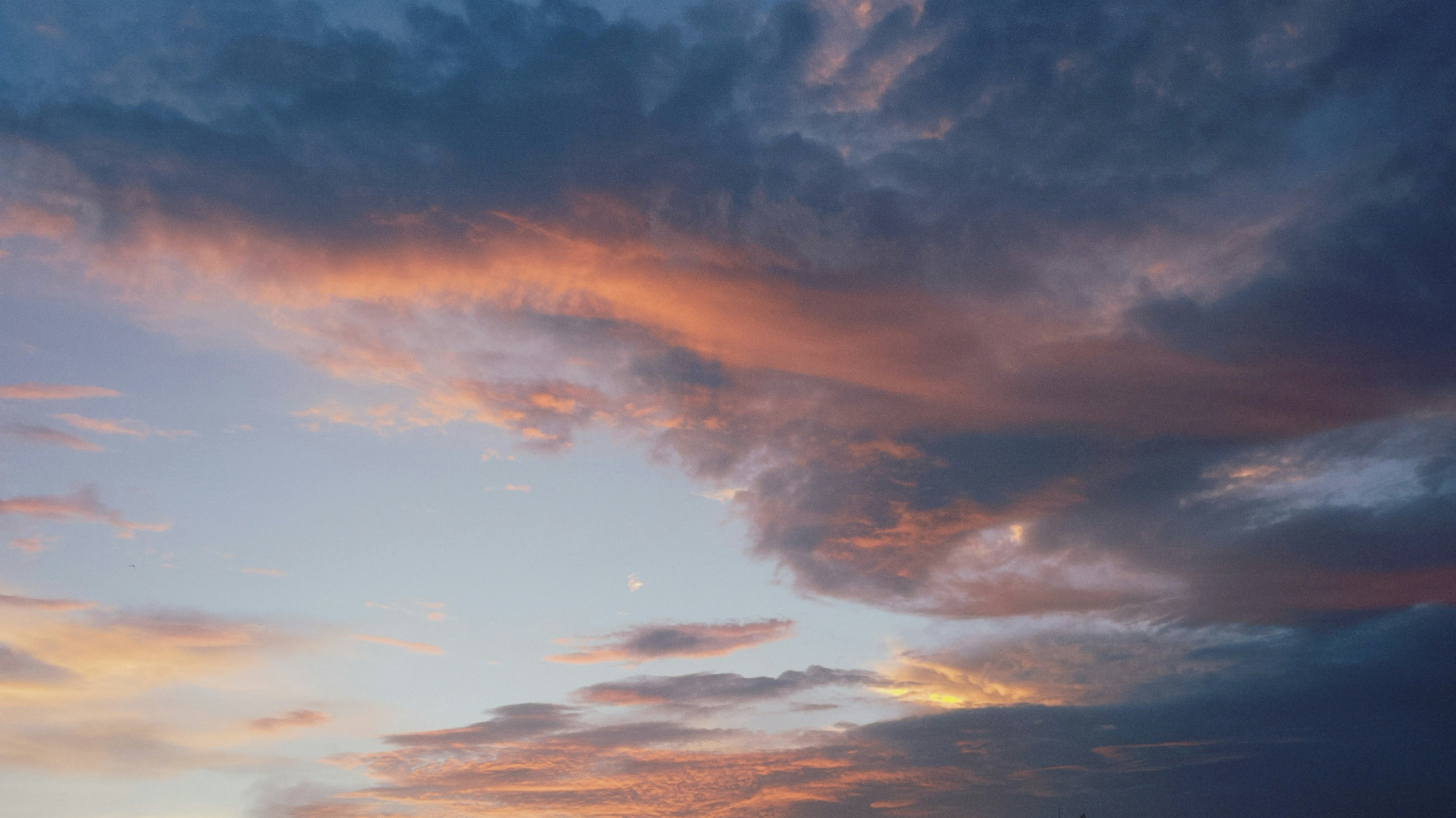 Dark blue and soft orange clouds in a vast sky