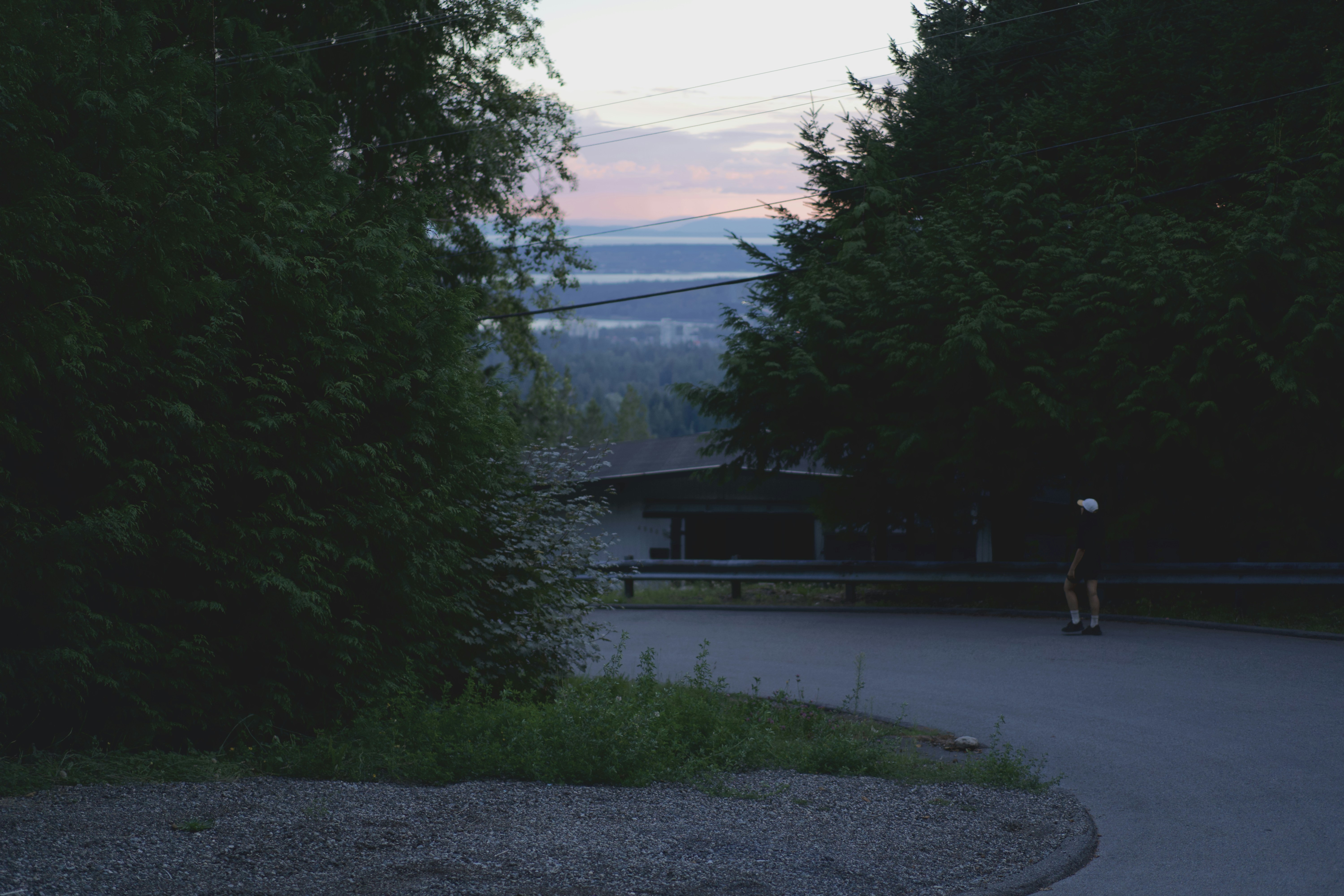 Walkers rounding a forested residential road at dusk in West Vancouver.