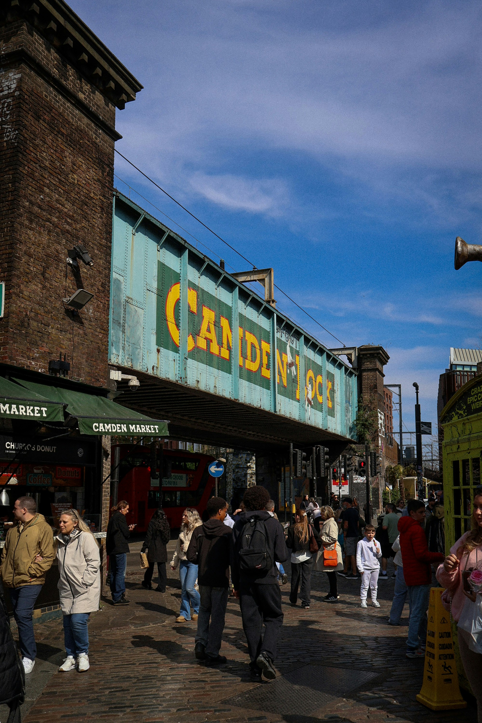 Des gens marchant sous un pont avec un grand panneau Camden Lock à Londres