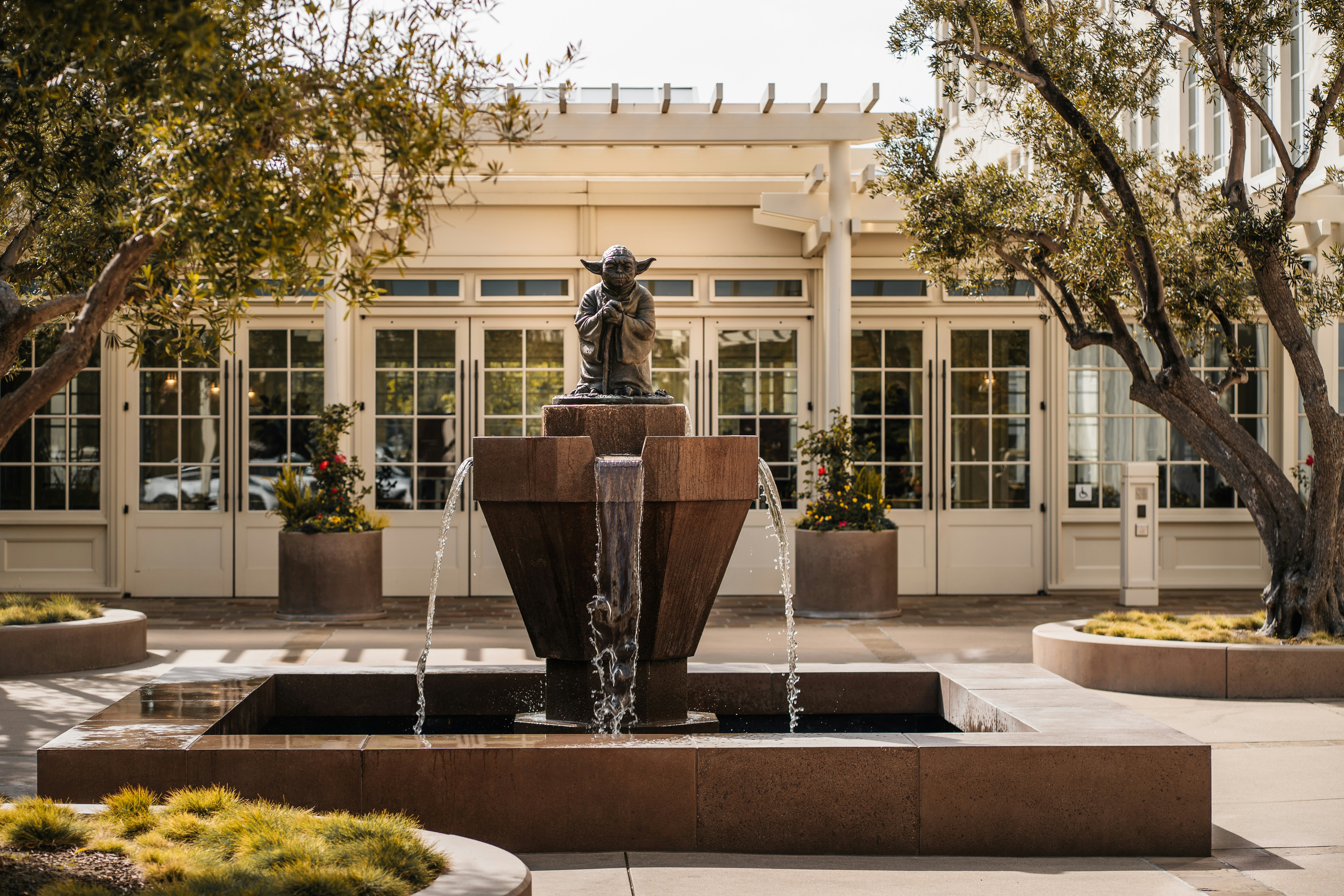 Eine Bronzestatue von Yoda auf einem steinernen Brunnen in einem Innenhof