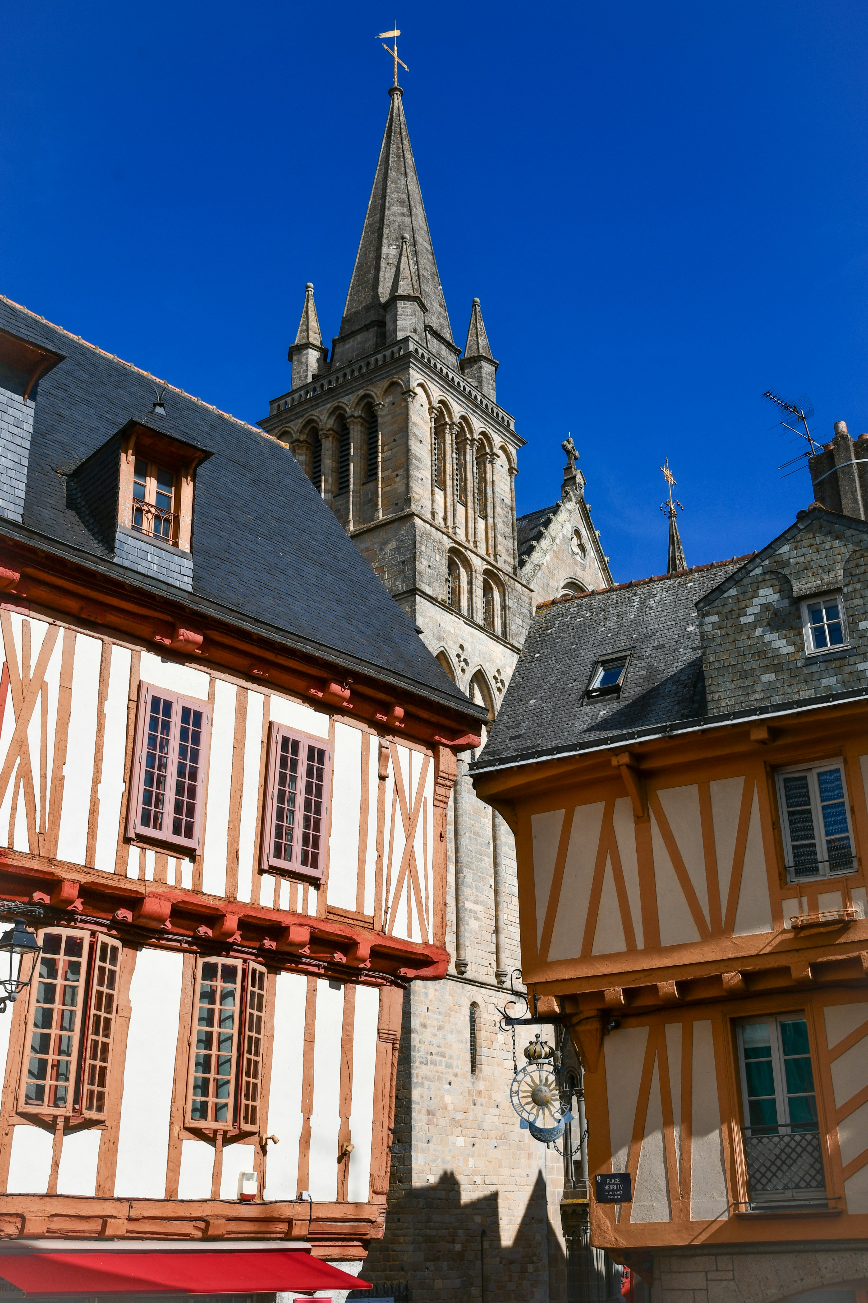 Fachwerkhäuser mit Schieferdächern neben einem hohen Steinkirchturm in Frankreich