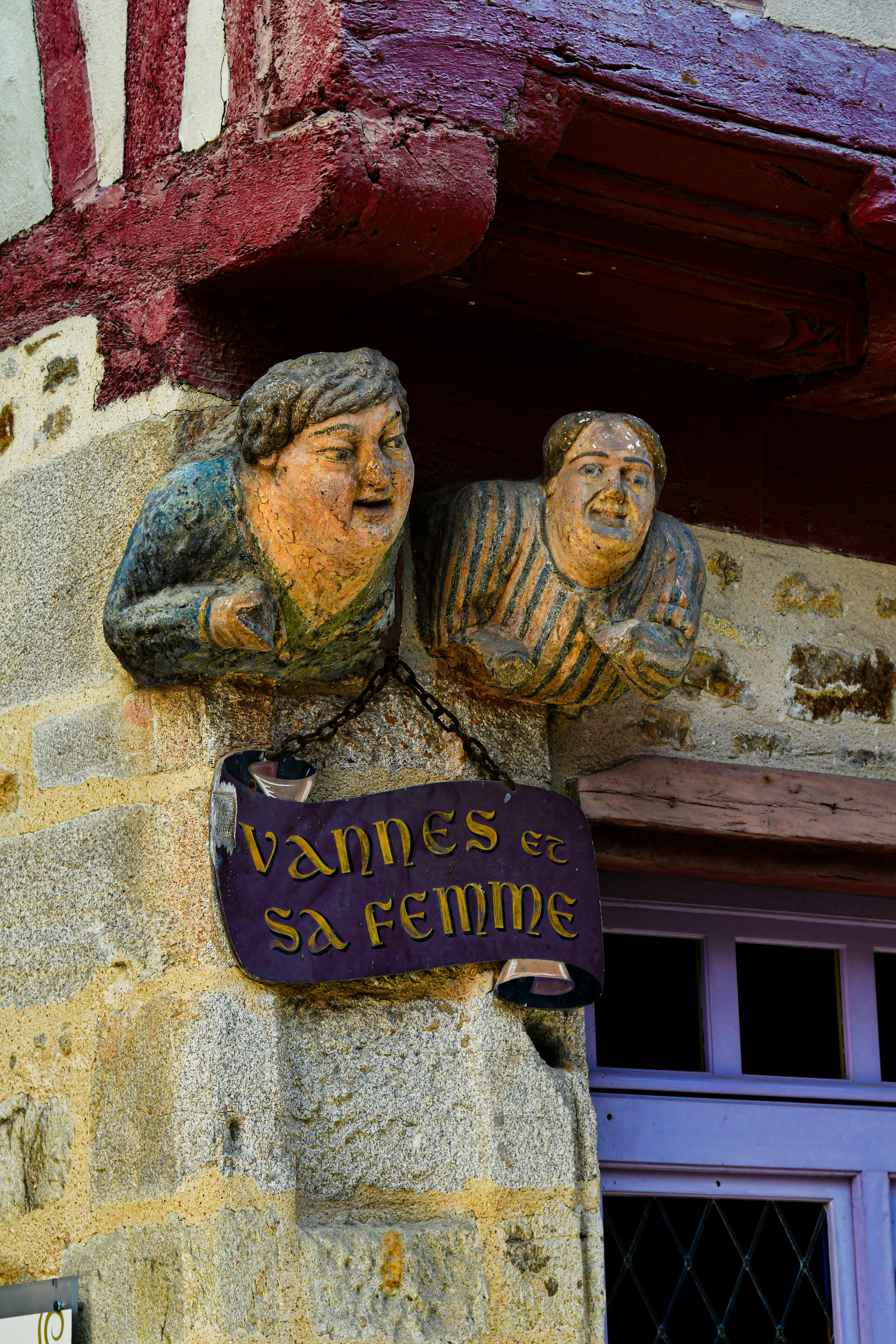 Bemalte Steinbüsten über einem Schild mit der Aufschrift "VANNES ET SA FEMME" auf einem Gebäude