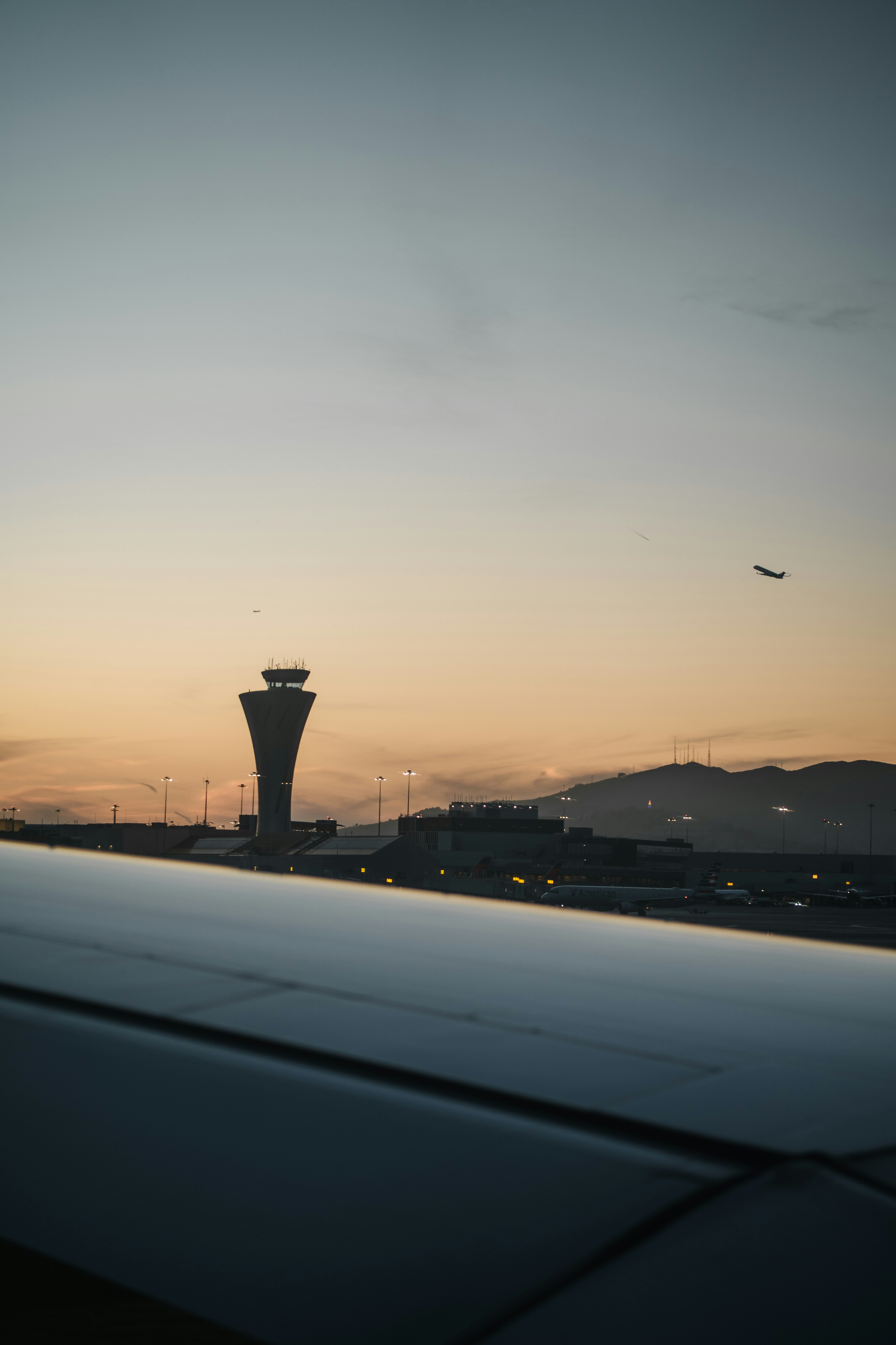 Ein Flughafen-Kontrollturm und ferne Berge unter einem sanft orangefarbenen Himmel