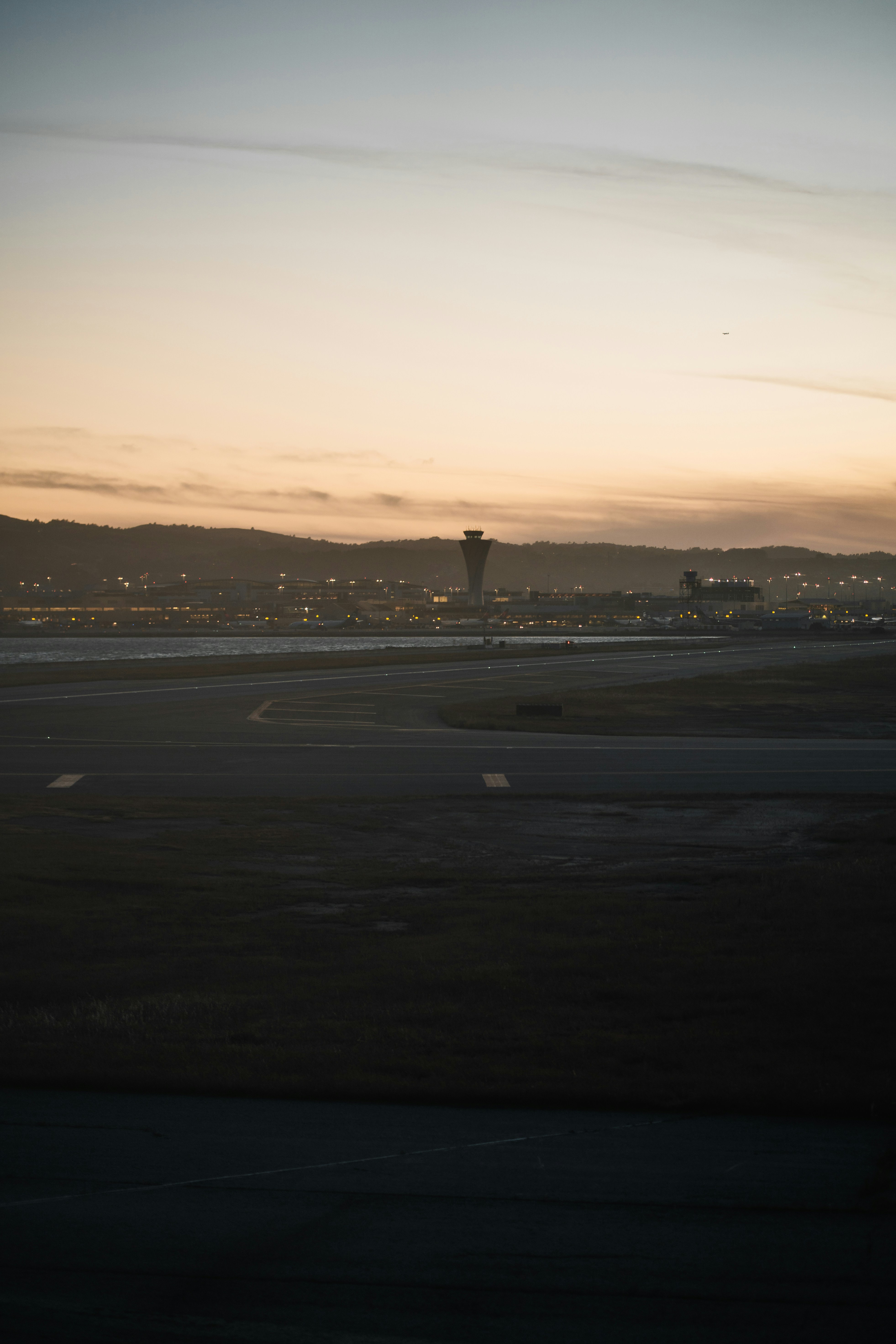 Eine Flughafenstartbahn bei niedriger Sonne mit einem entfernten Kontrollturm und einem Terminal