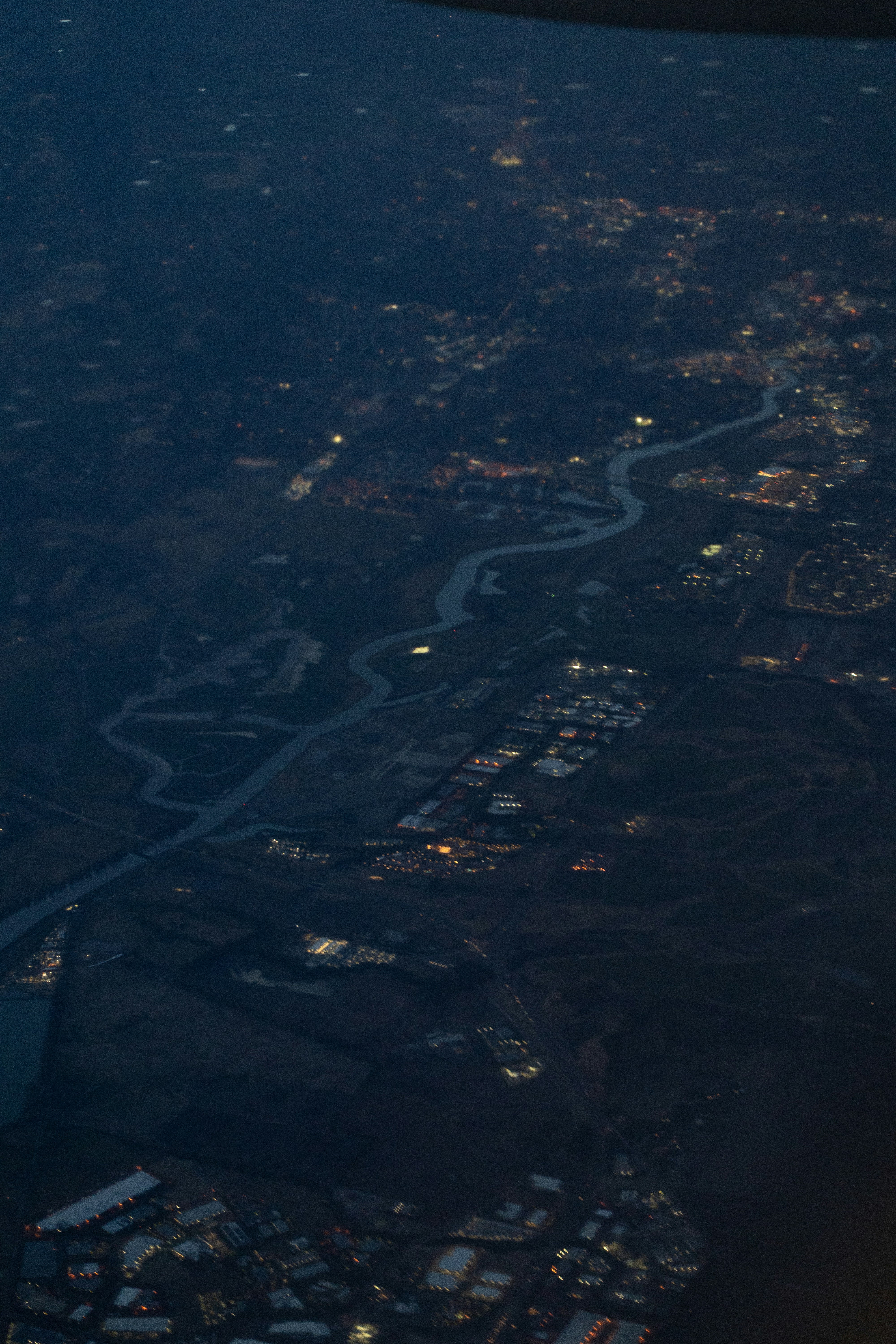 Eine Luftaufnahme eines sich windenden Flusses durch eine Landschaft mit verstreuten Stadtlichtern