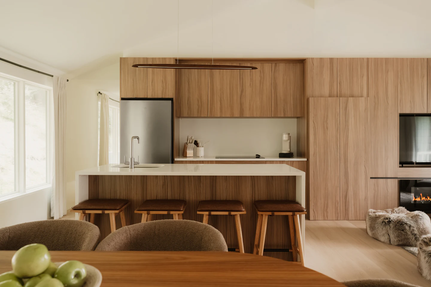 Walnut kitchen cabinetry with a white island and leather stools