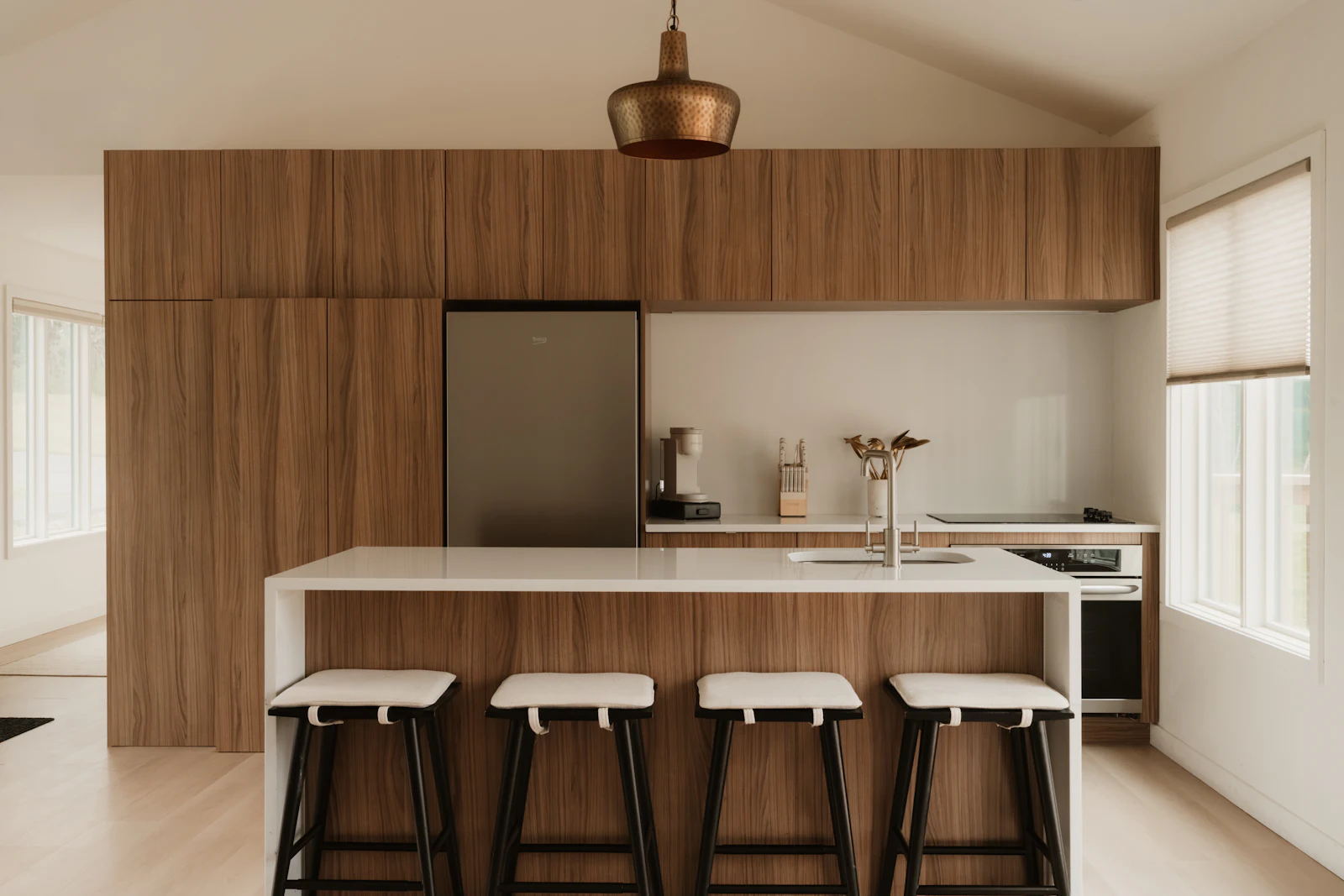 Cocina con columnas en madera, isla blanca y cuatro taburetes