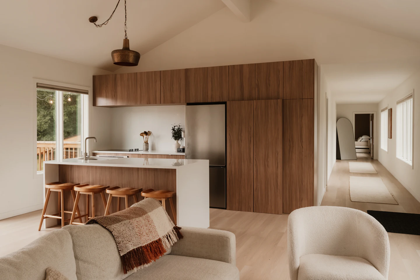 Modern kitchen with walnut cabinets, a white island and four wood stools