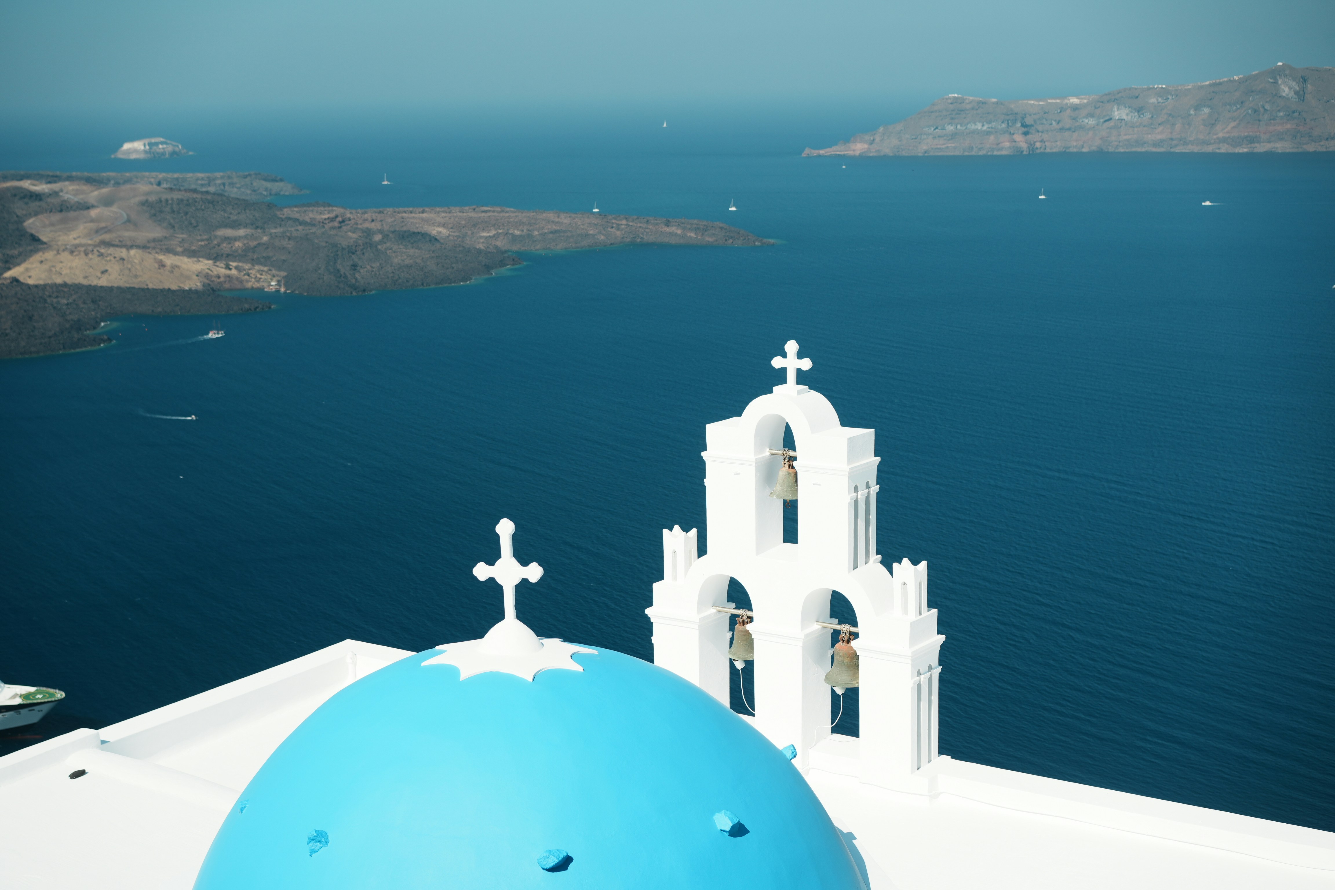 ギリシャ・サントリーニの青いドームと海を見下ろす白い鐘楼