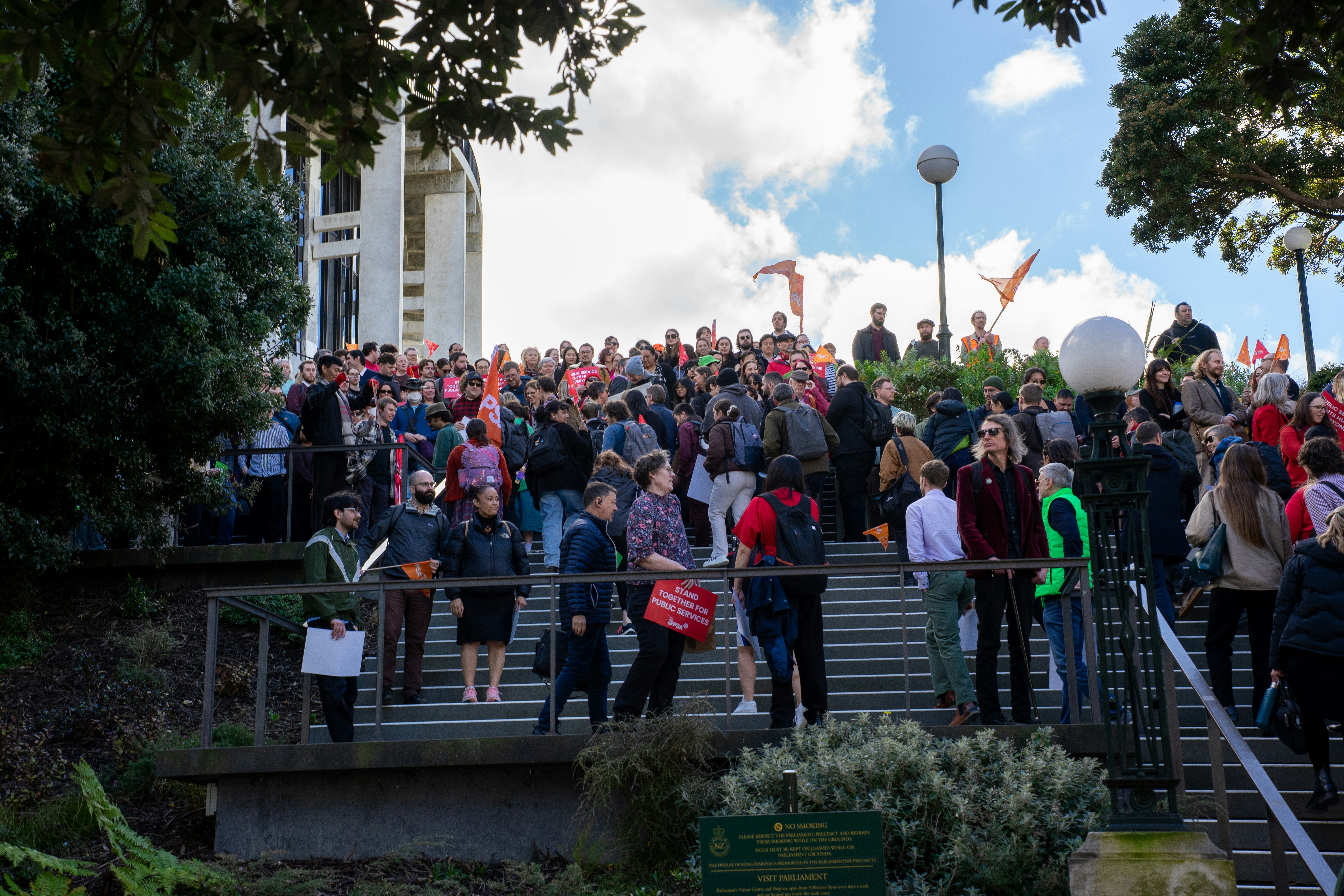 A large group of people walking up concrete stairs toward a government building