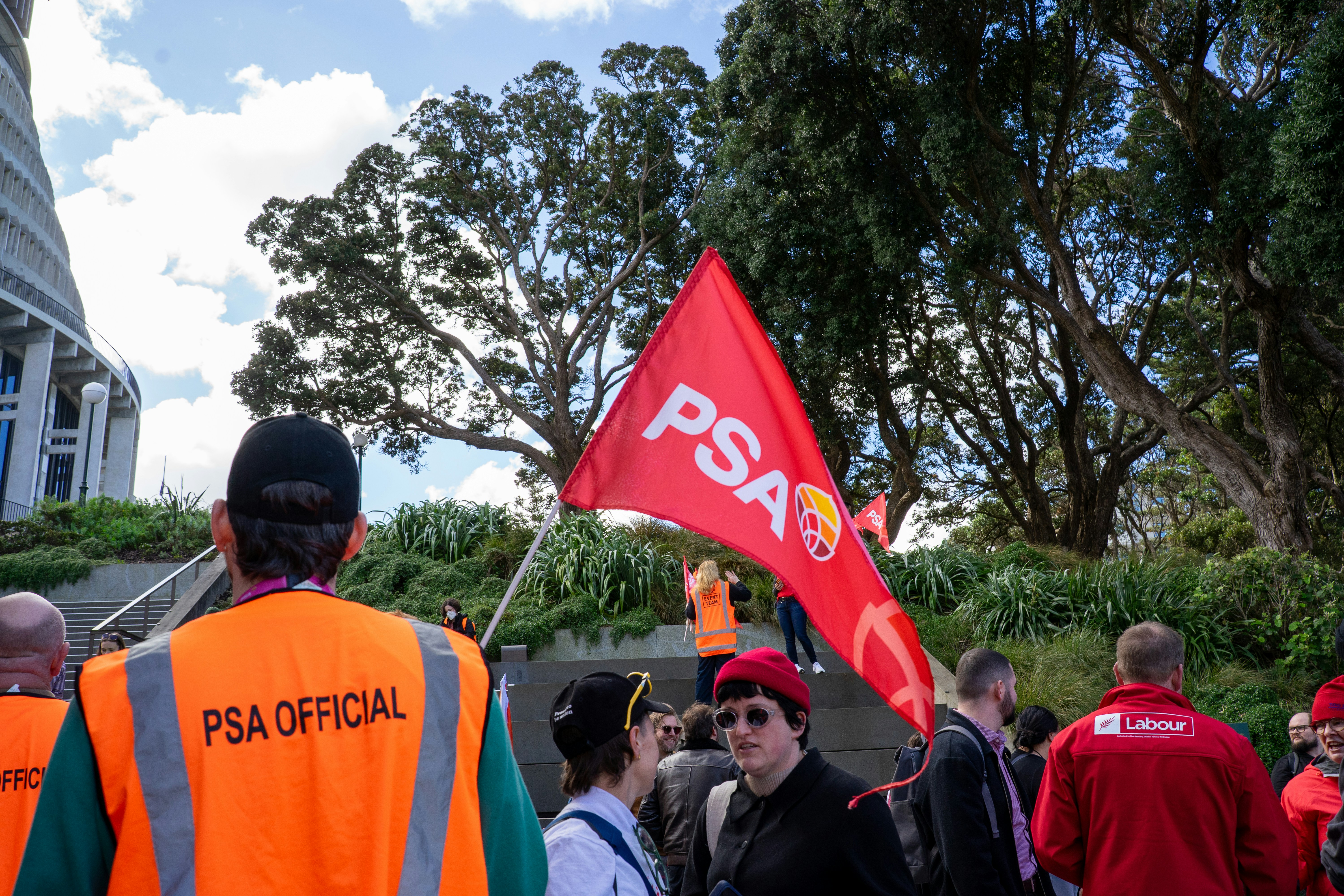 Une personne en gilet orange tenant un drapeau rouge de la PSA lors d’une manifestation