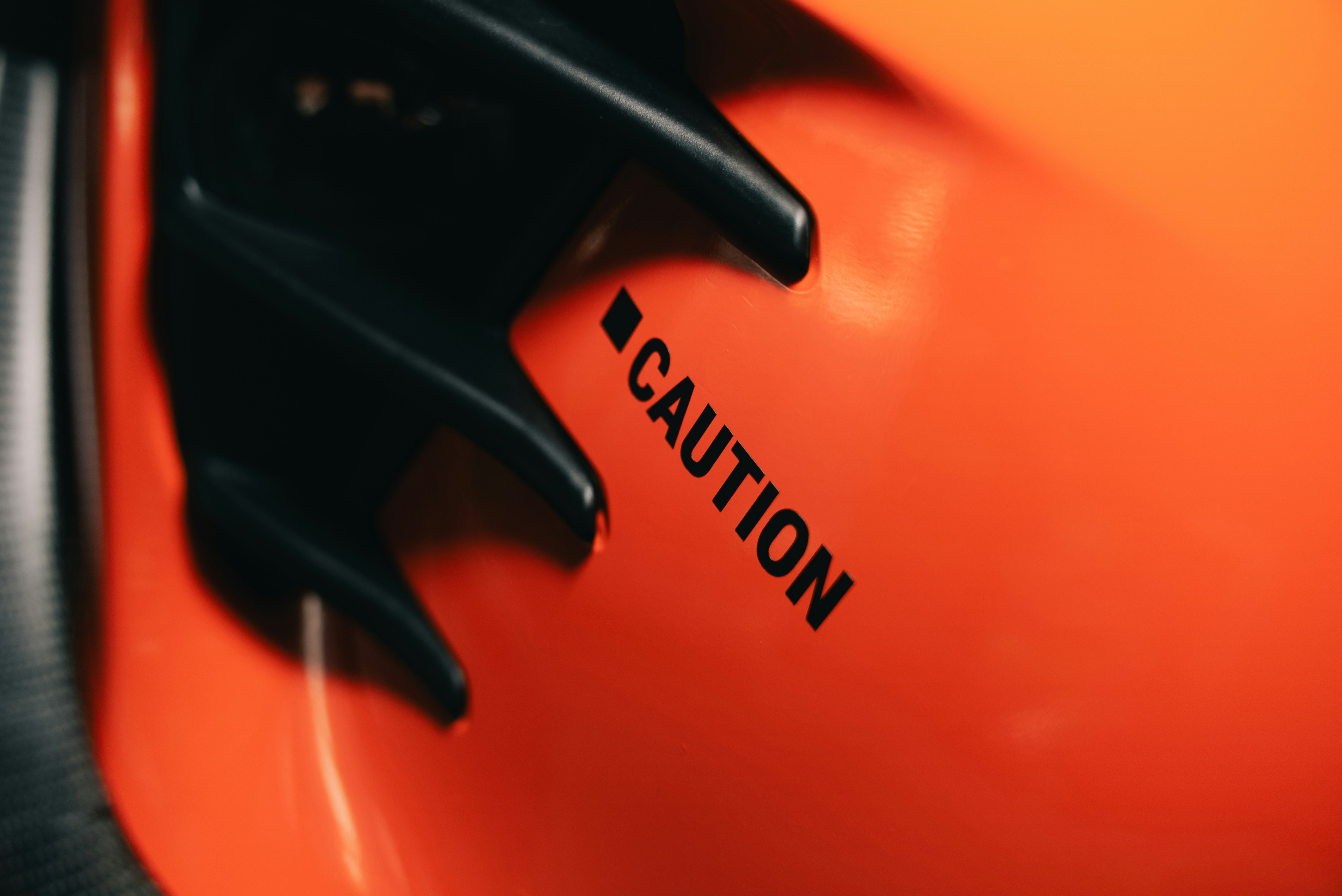 The word CAUTION printed in black on a bright orange surface with black trim