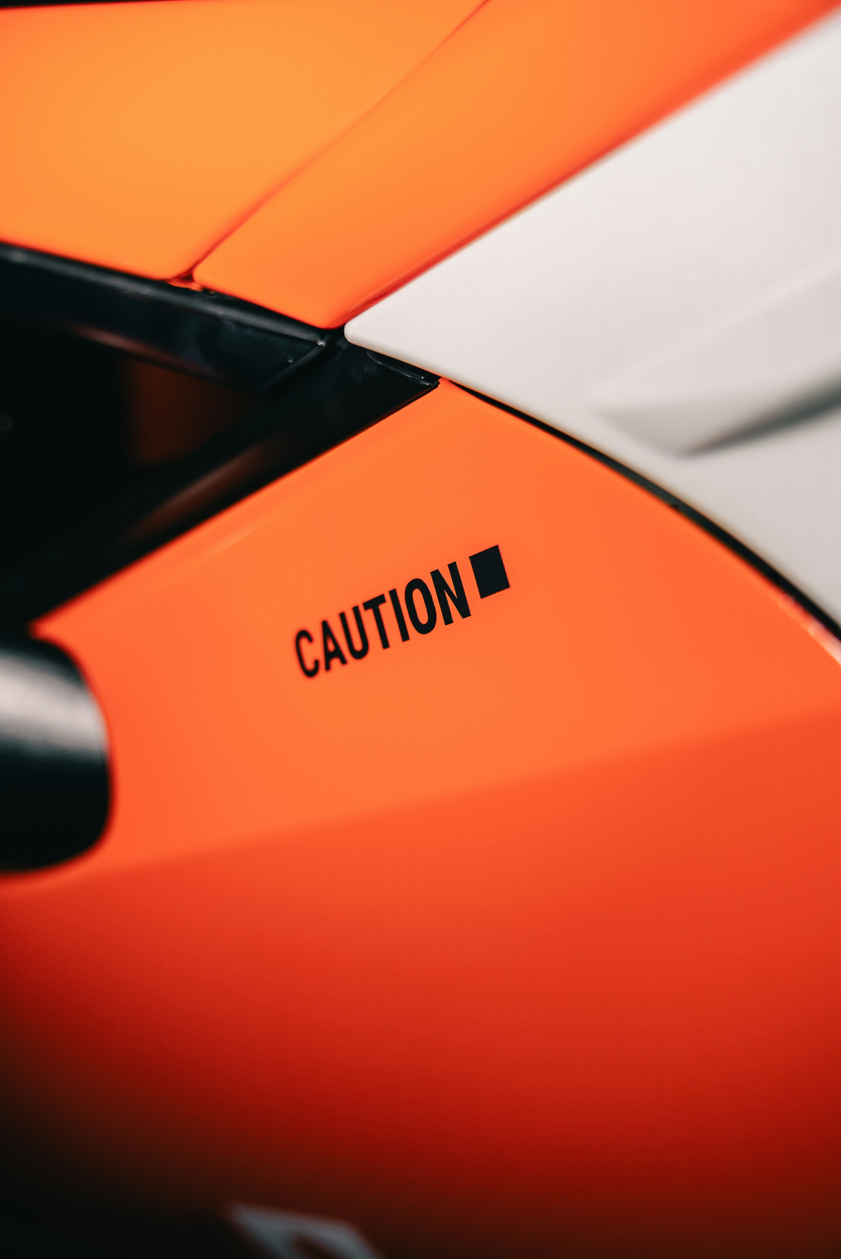 A bright orange surface with a black label reading CAUTION
