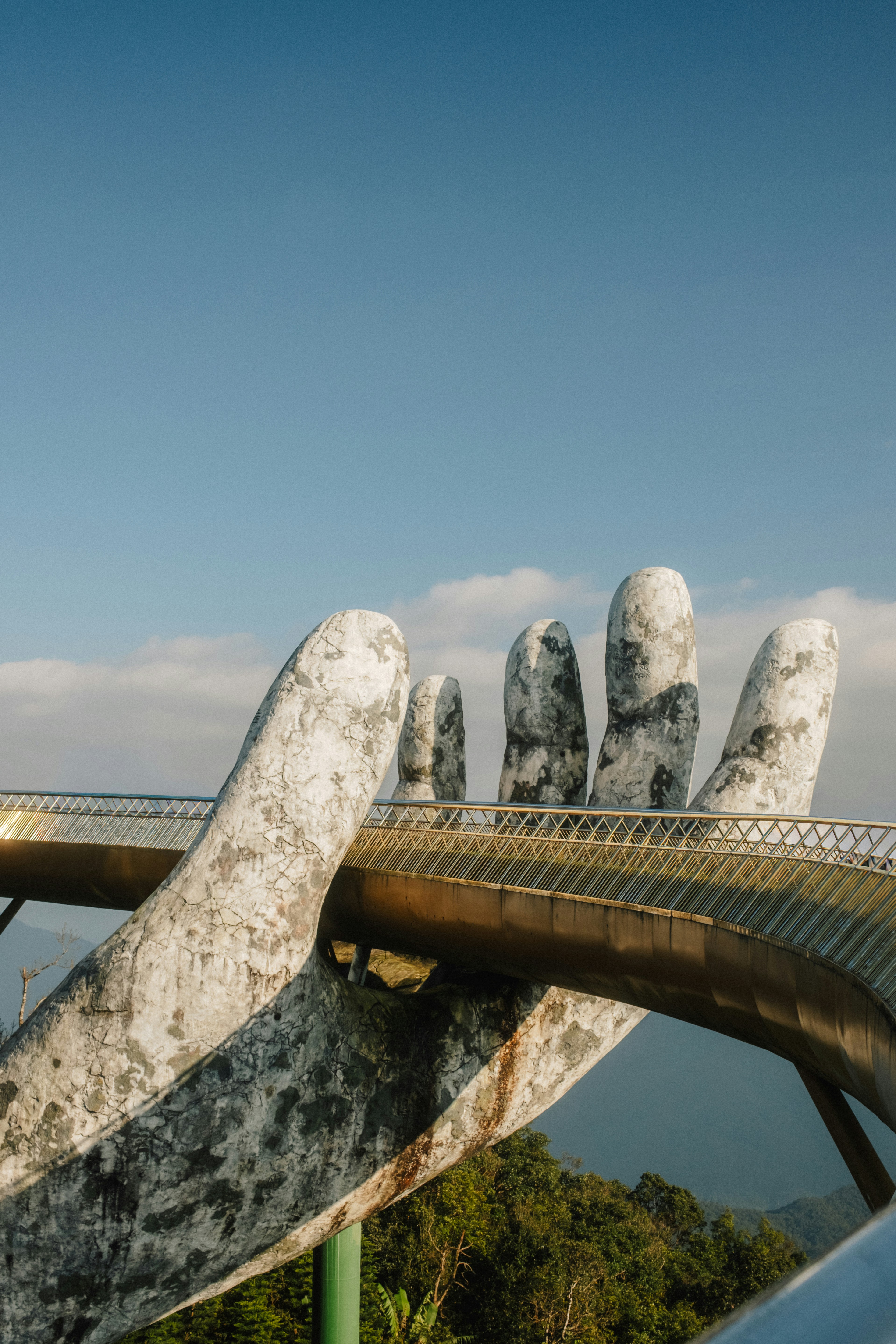 Photo of A golden pedestrian bridge held by a giant stone hand in Da Nang, Vietnam by Vincent Yap
