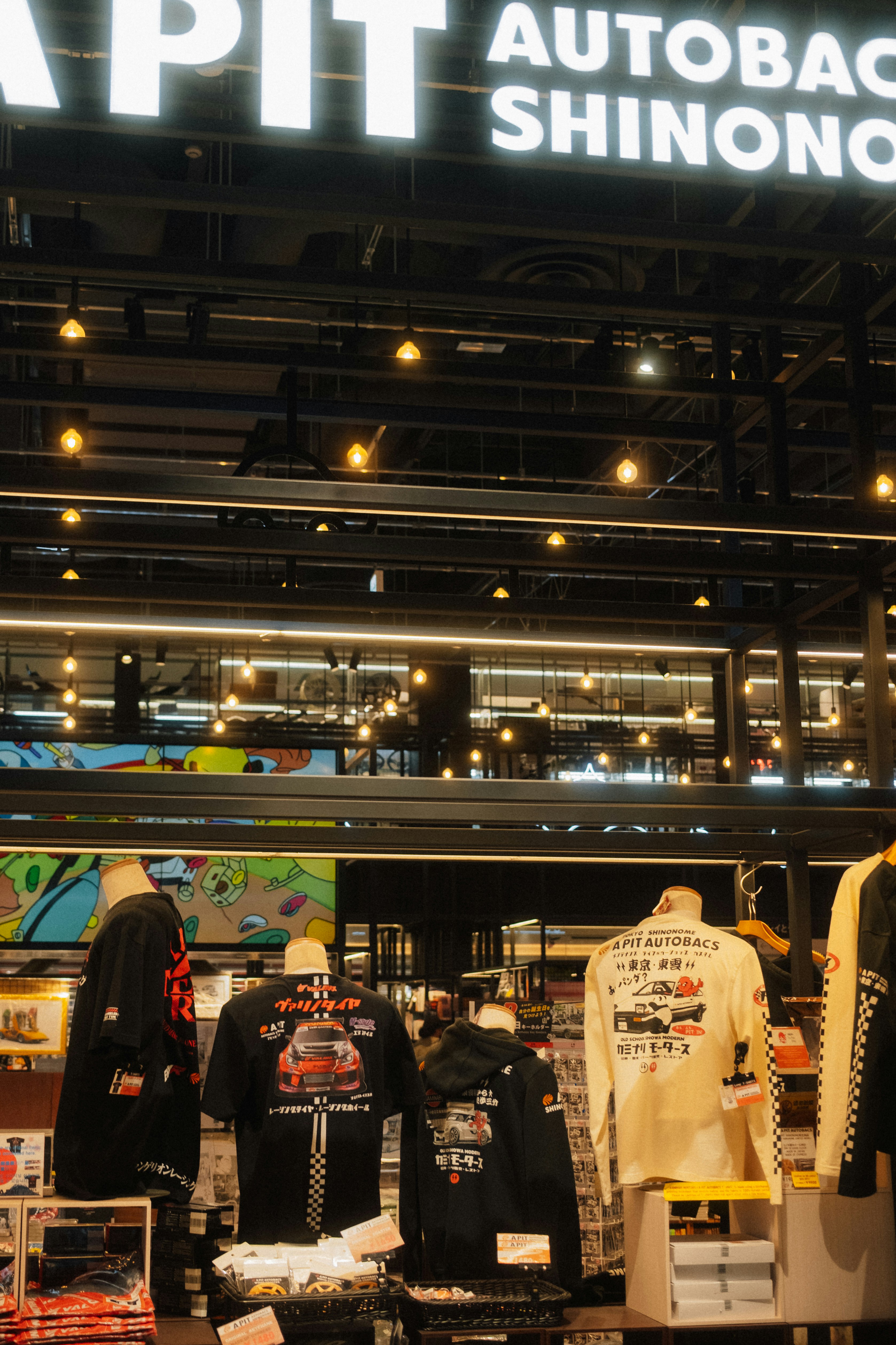 Mannequins wearing graphic t-shirts and hoodies in a retail store with hanging lights