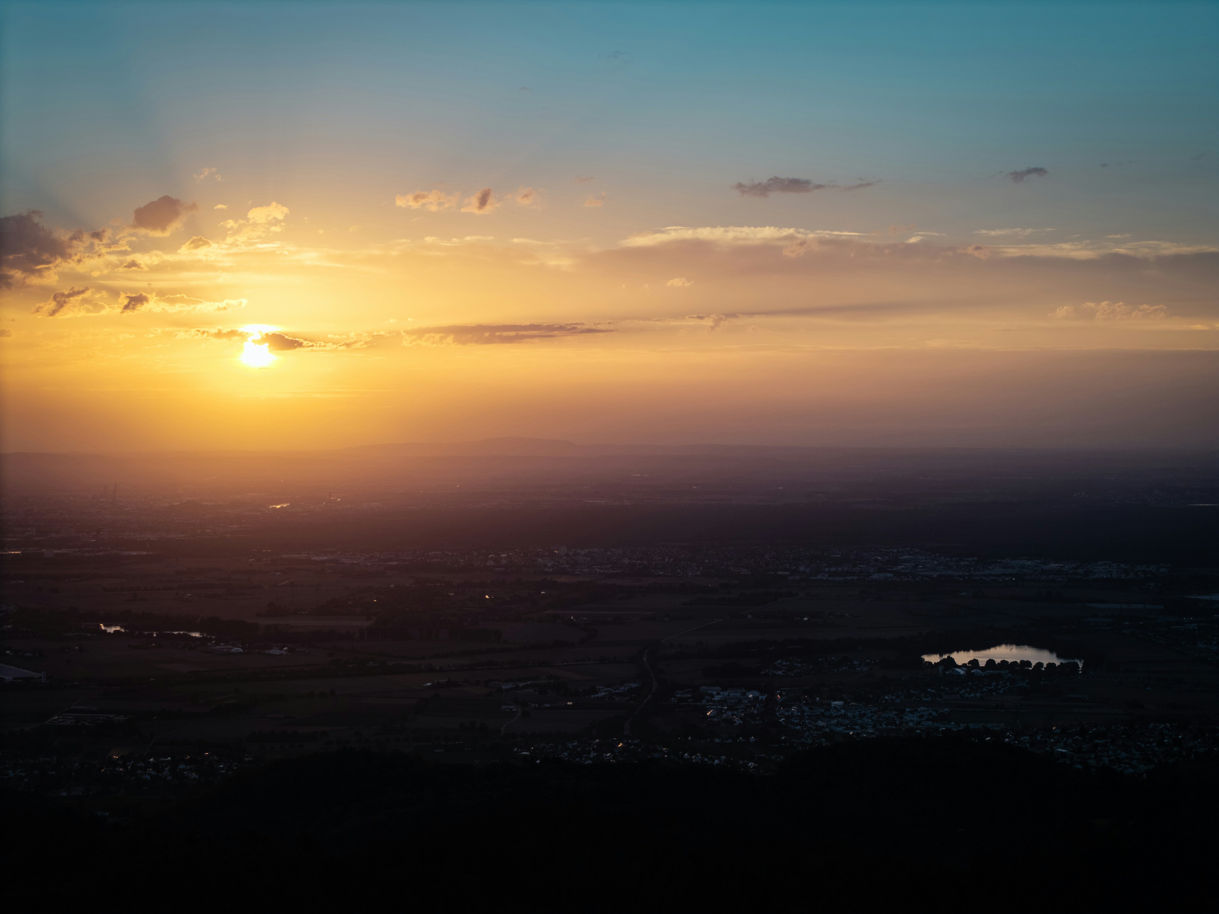 A low sun casting golden light over a vast landscape with a small lake