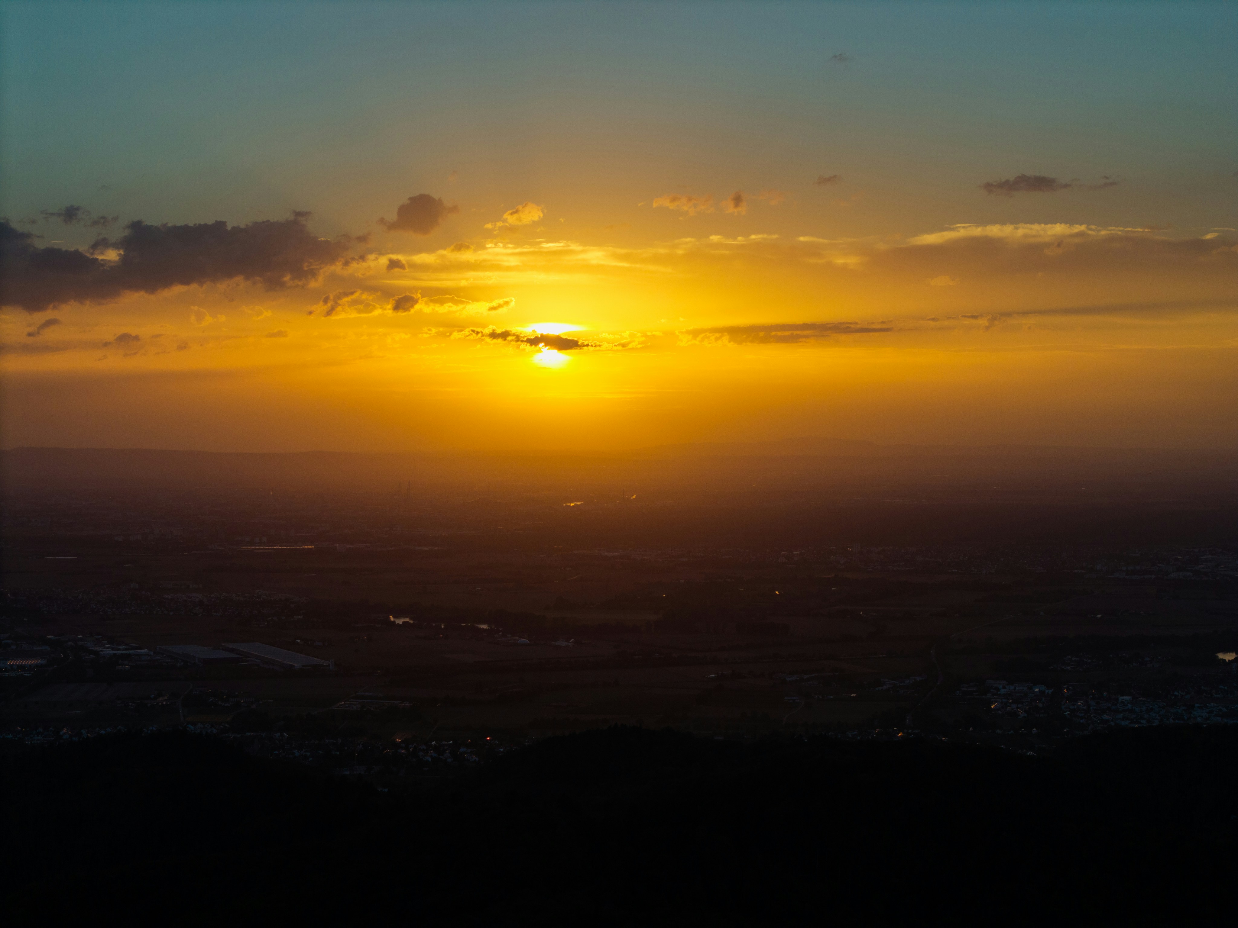 A low sun glowing in a warm orange sky above a dark landscape