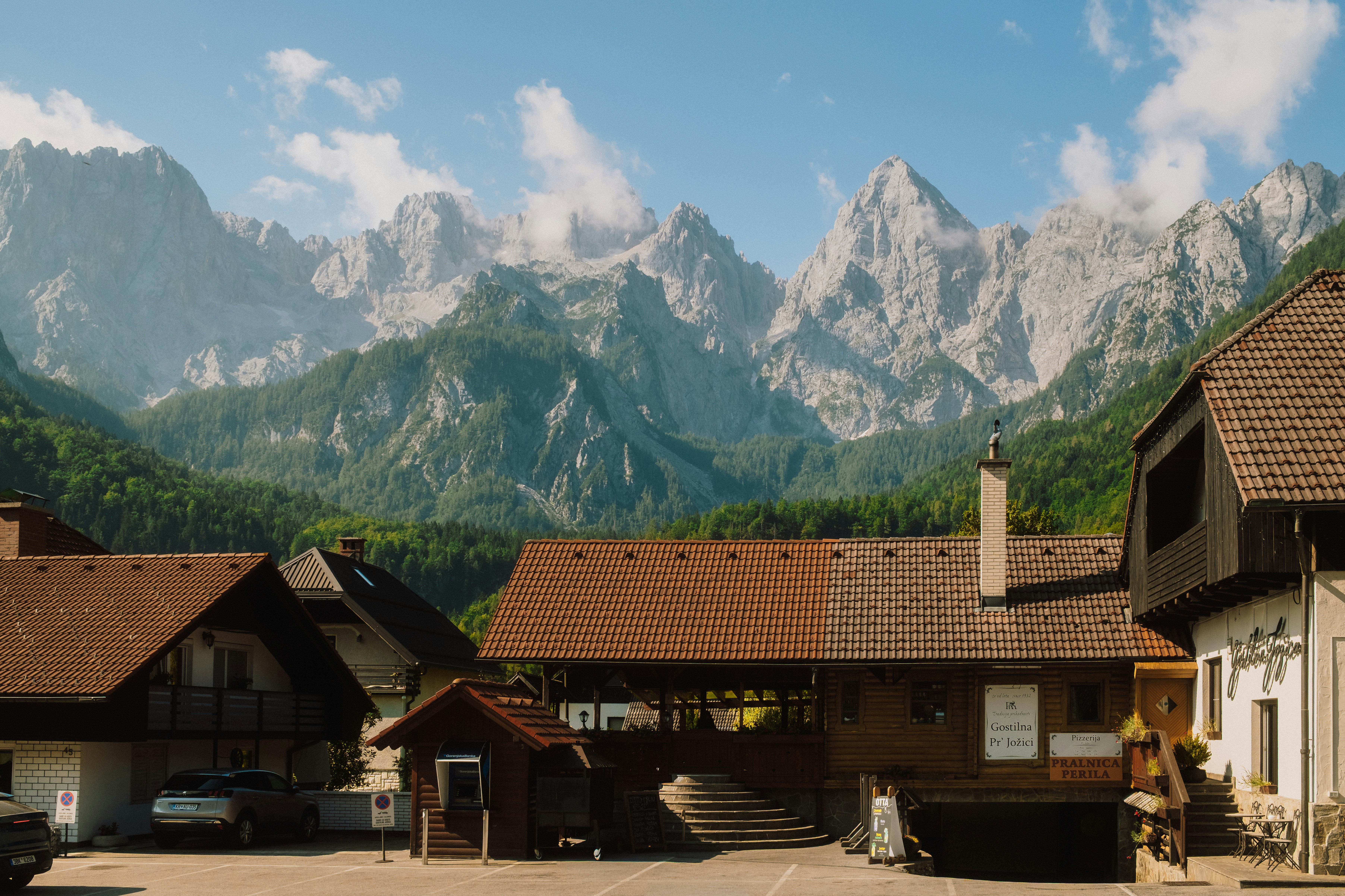 Traditional houses with tiled roofs beneath jagged limestone peaks in the Kamnik-Savinja Alps