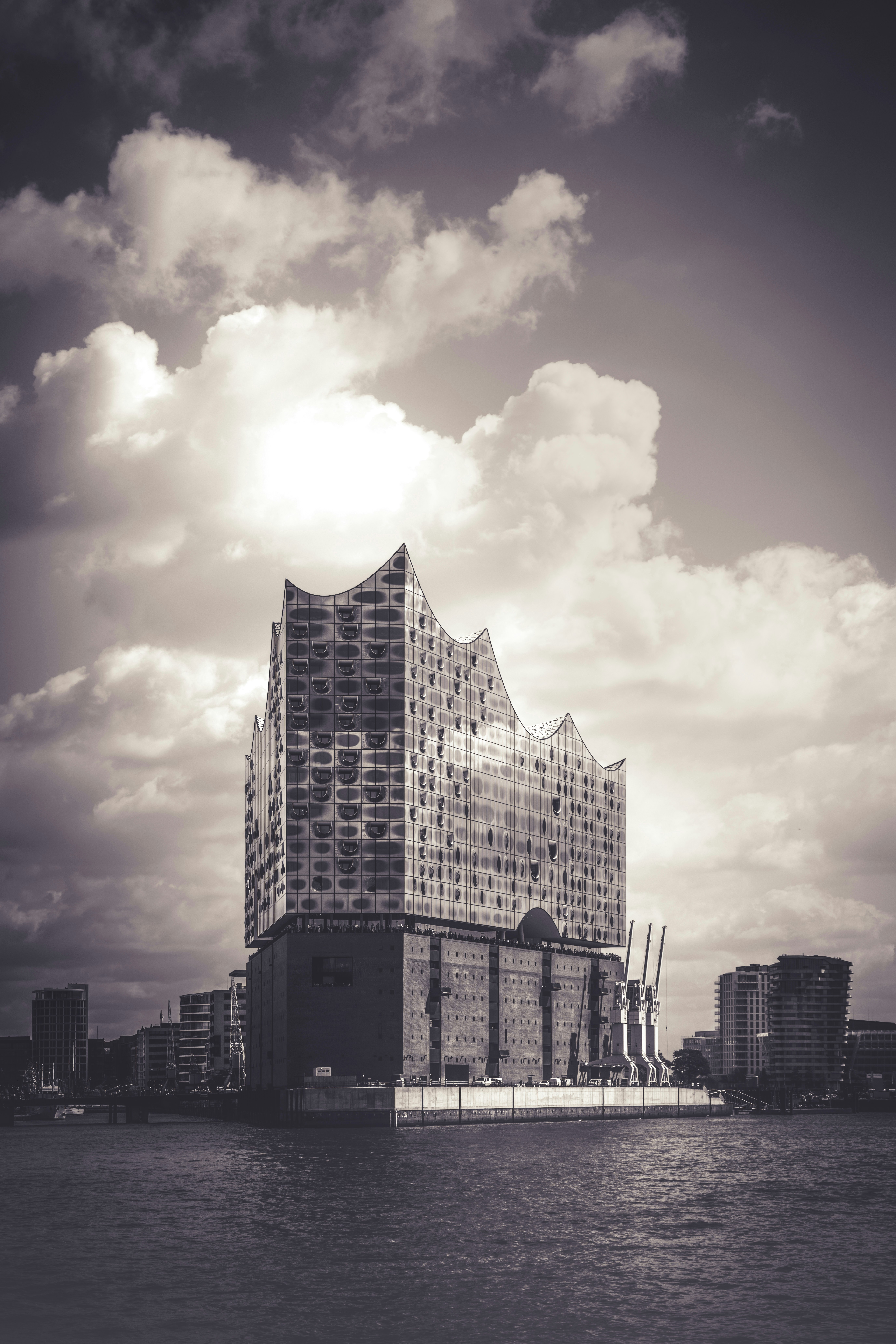 Der Elbphilharmonie-Konzertsaal am Wasser in Hamburg unter bewölktem Himmel