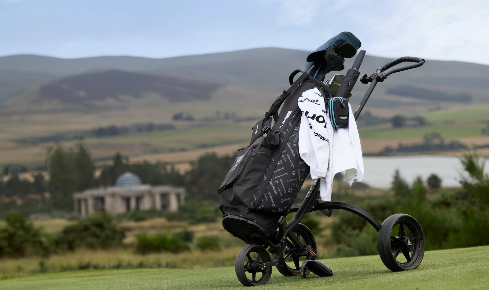 Black golf bag on a push cart on the course