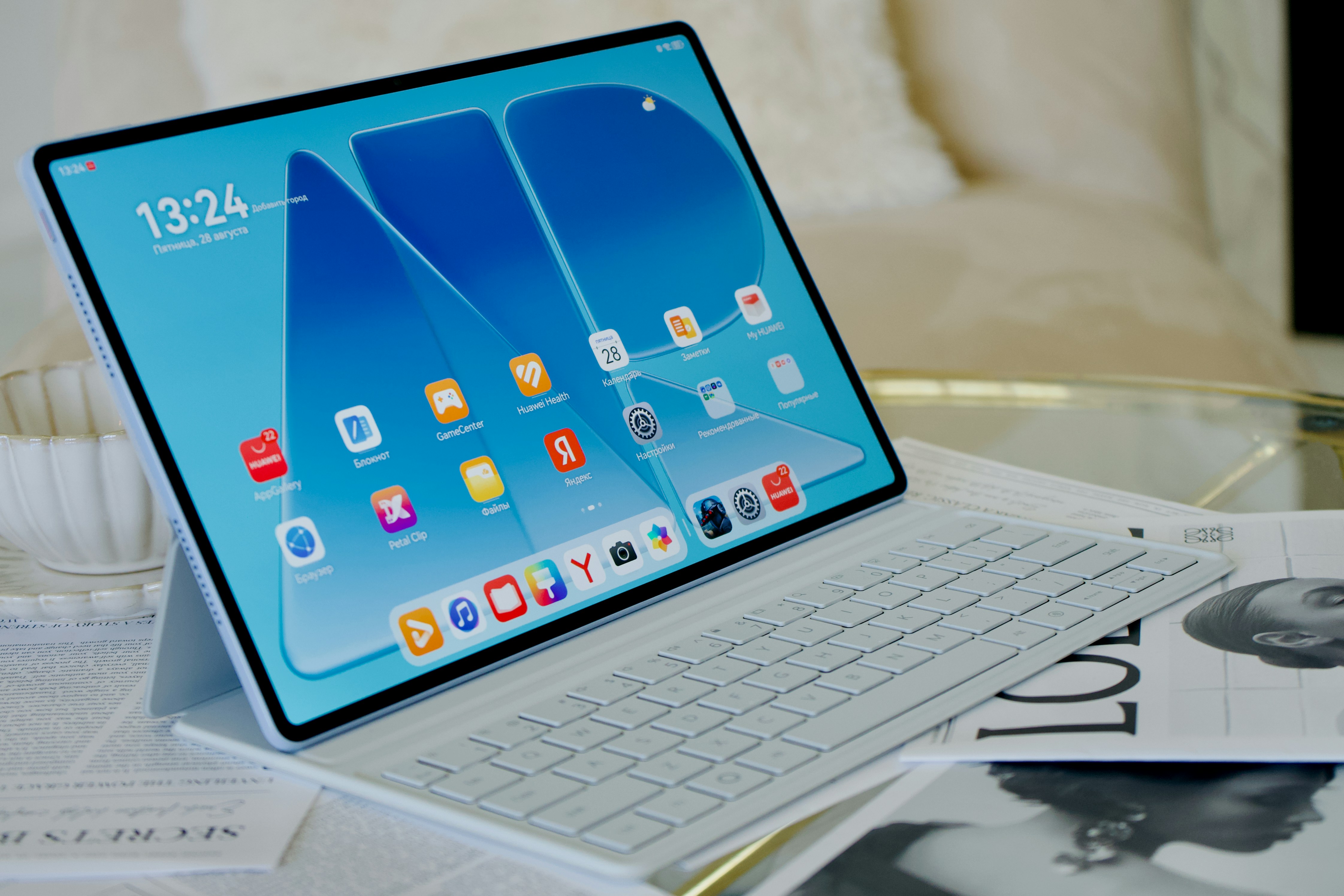 A tablet with a blue screen and keyboard cover on a glass table
