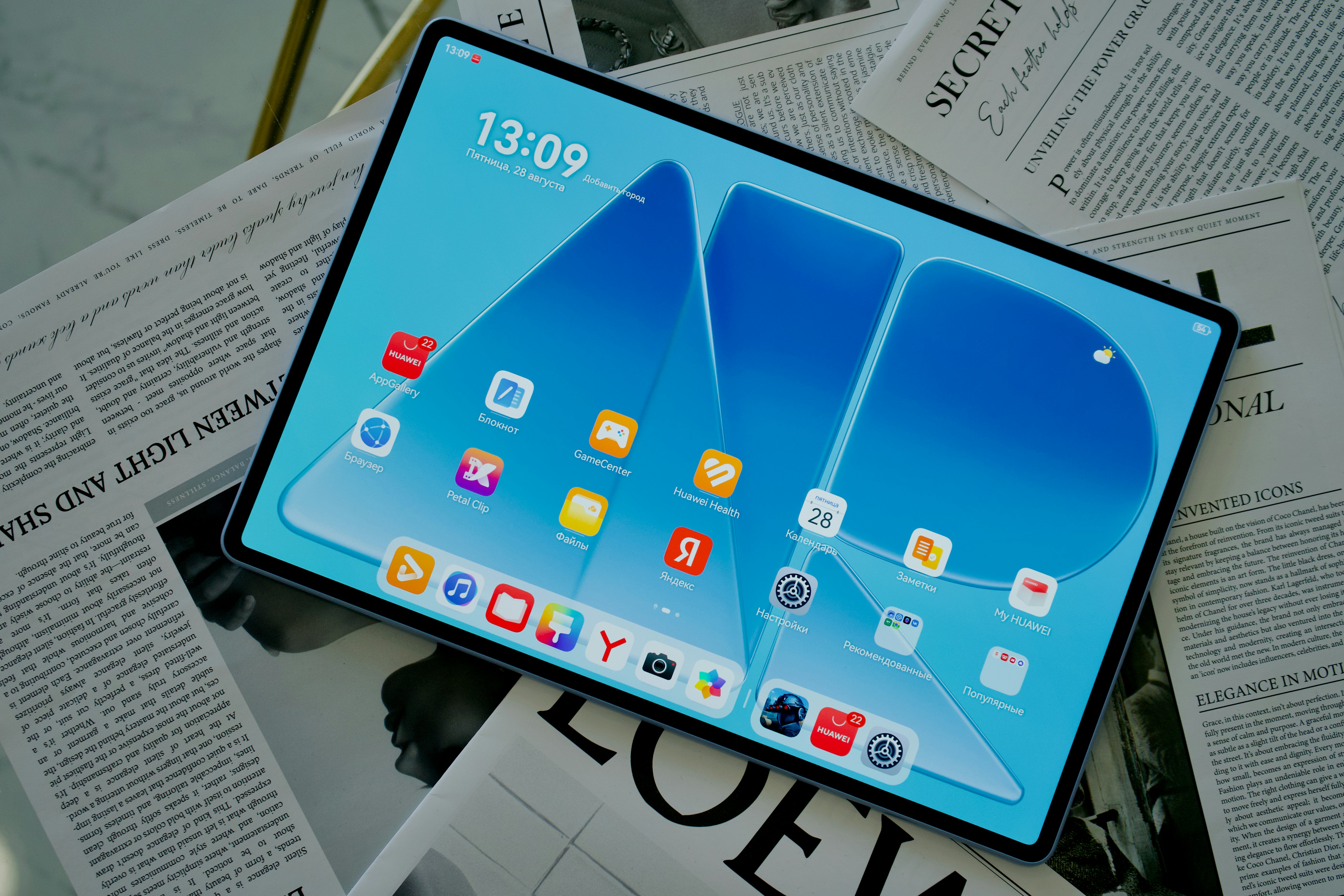 A tablet displaying a blue home screen with app icons on a newspaper