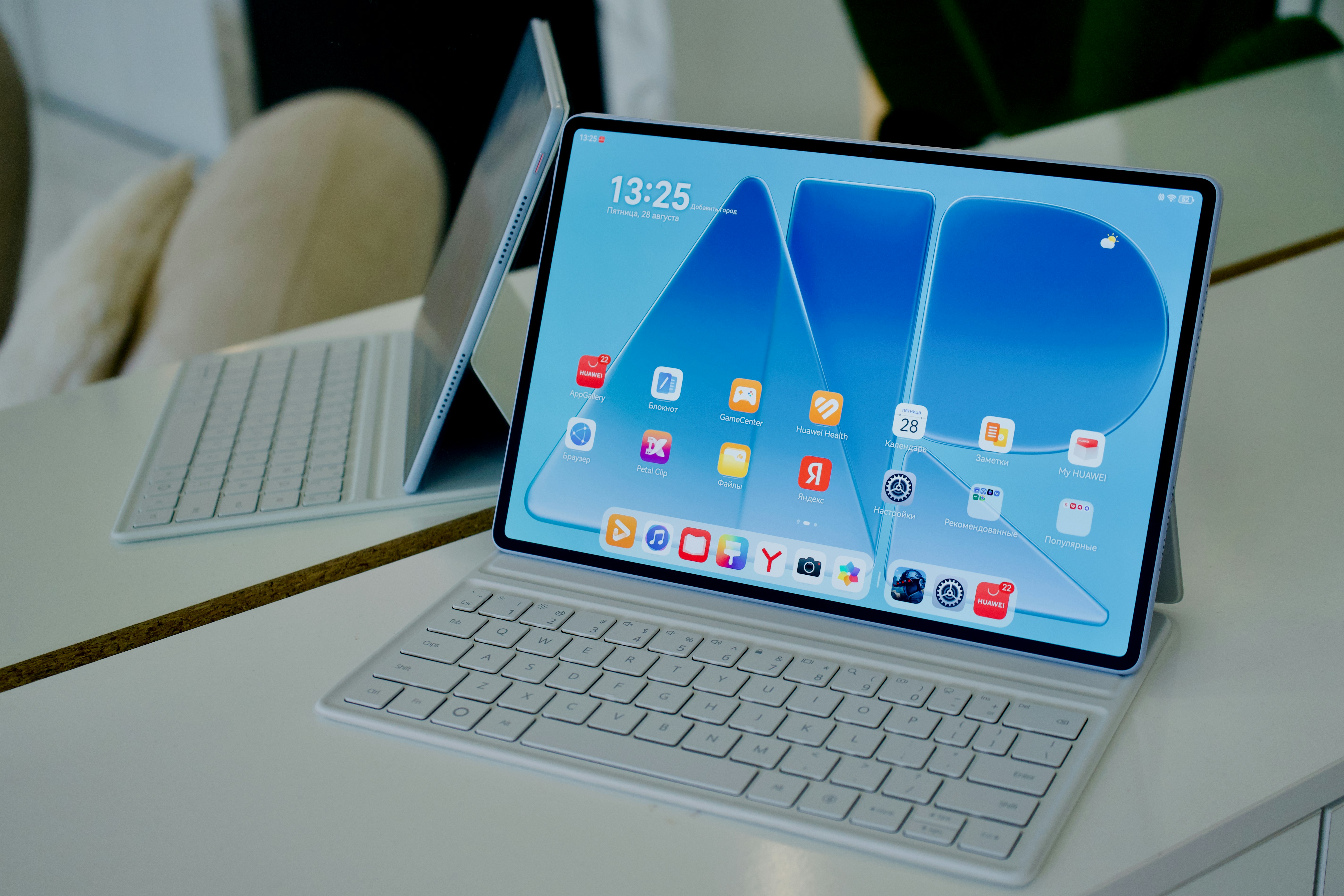 A tablet with a keyboard cover on a white desk with a reflection