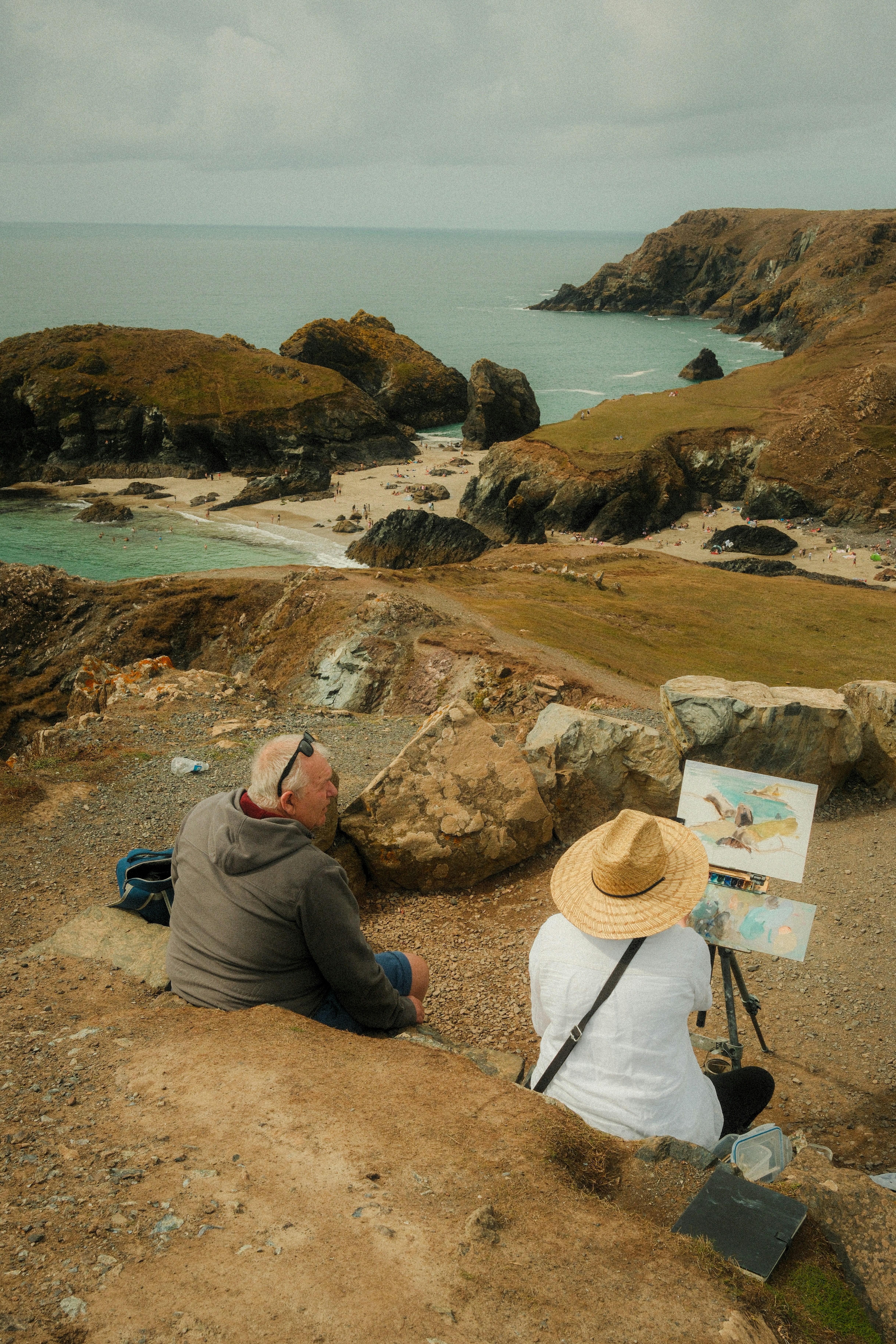 Photo of A person in a straw hat painting a coastal landscape on an easel by Yousef Salhamoud
