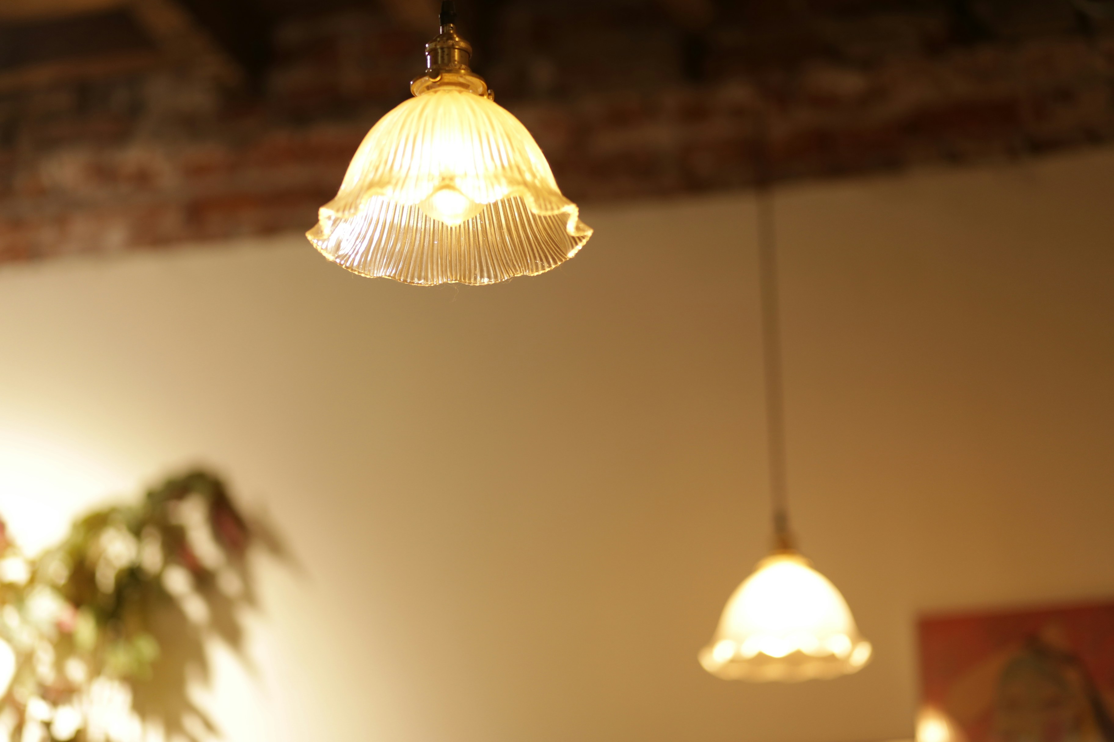 Two glowing fluted glass pendant lights hanging against a plain wall