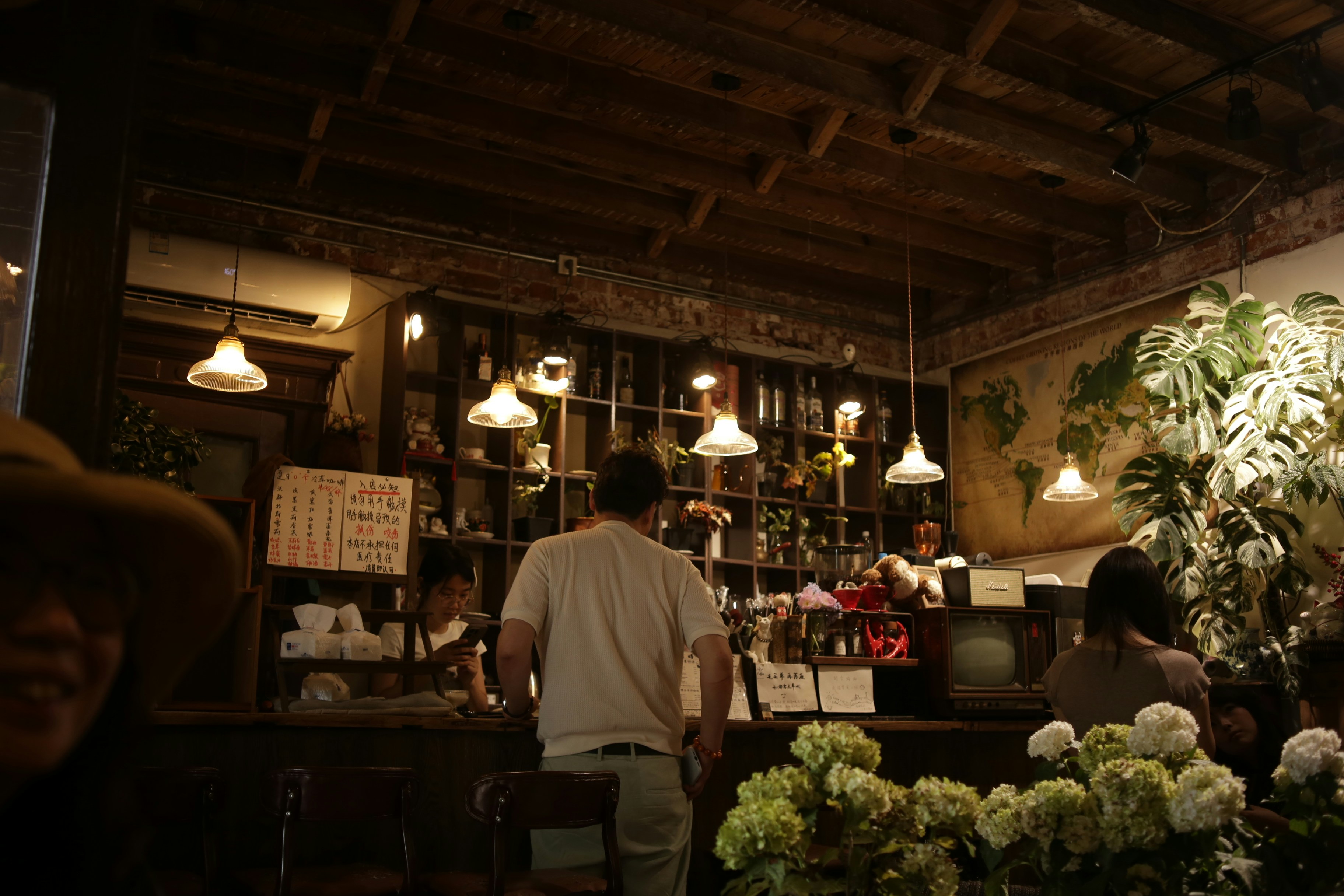 People at a wooden bar in a dimly lit cafe with hanging pendant lights