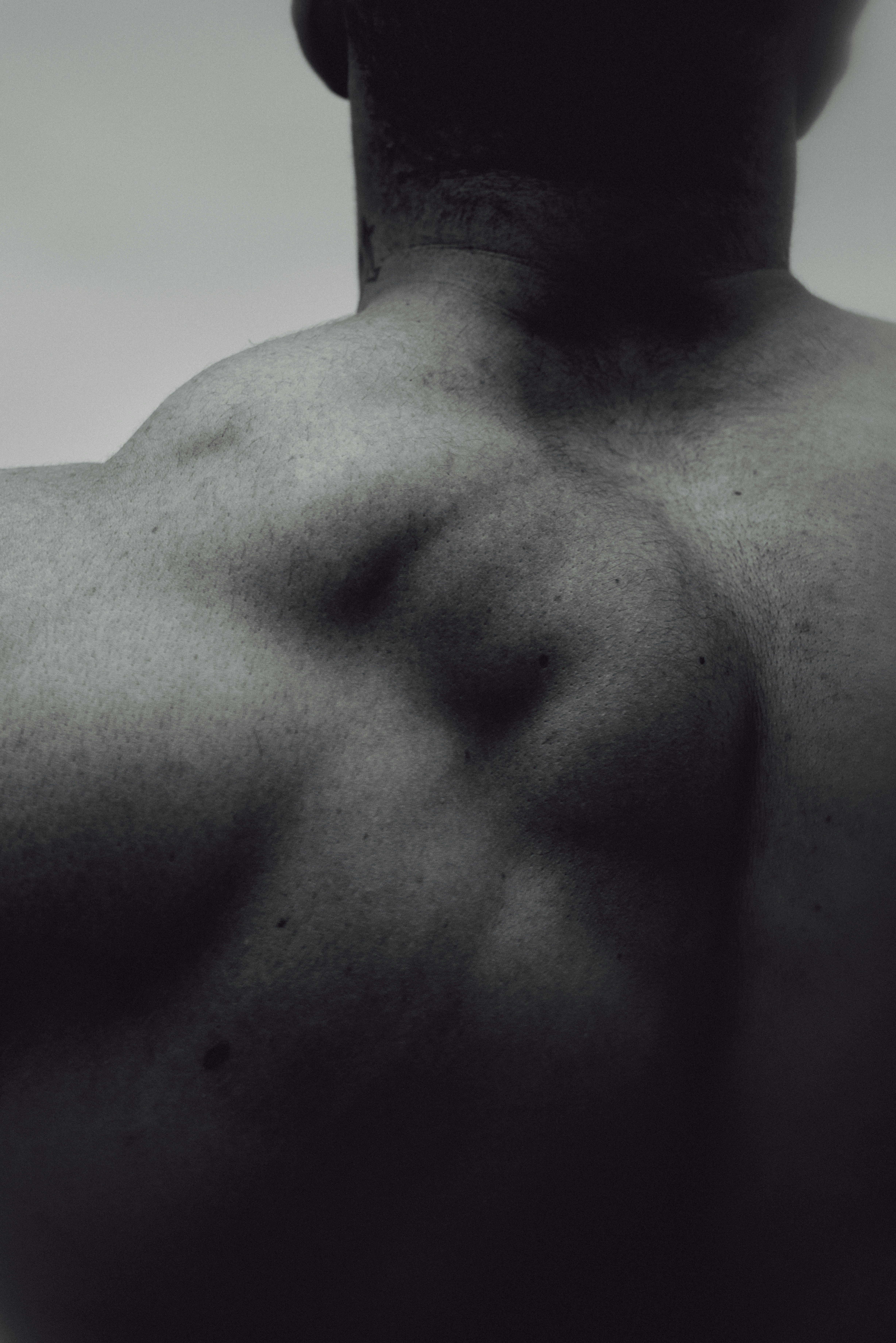 A close-up of a person's muscular back and shoulders in black and white