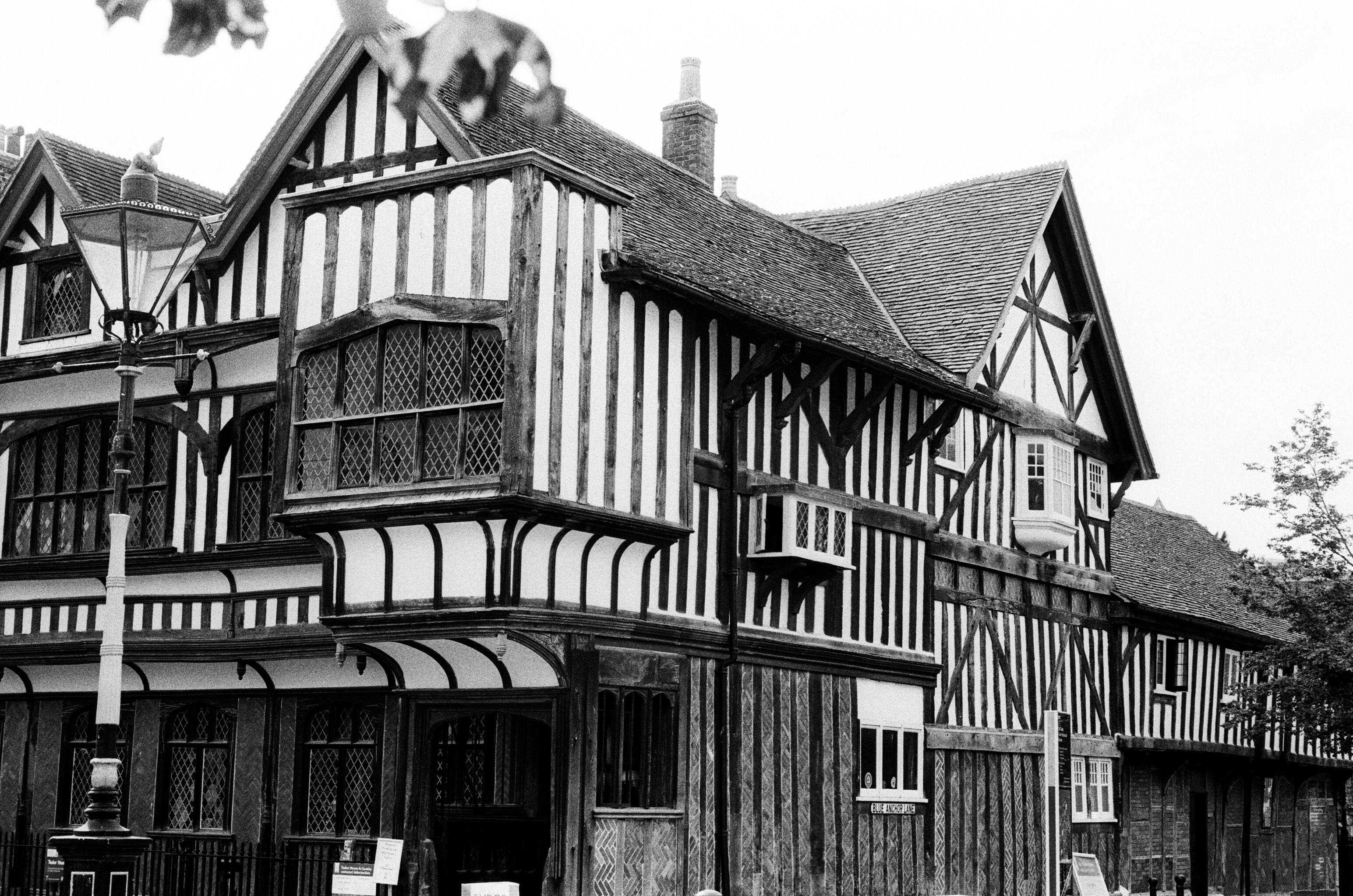 A black and white view of a timber-framed building with leaded windows