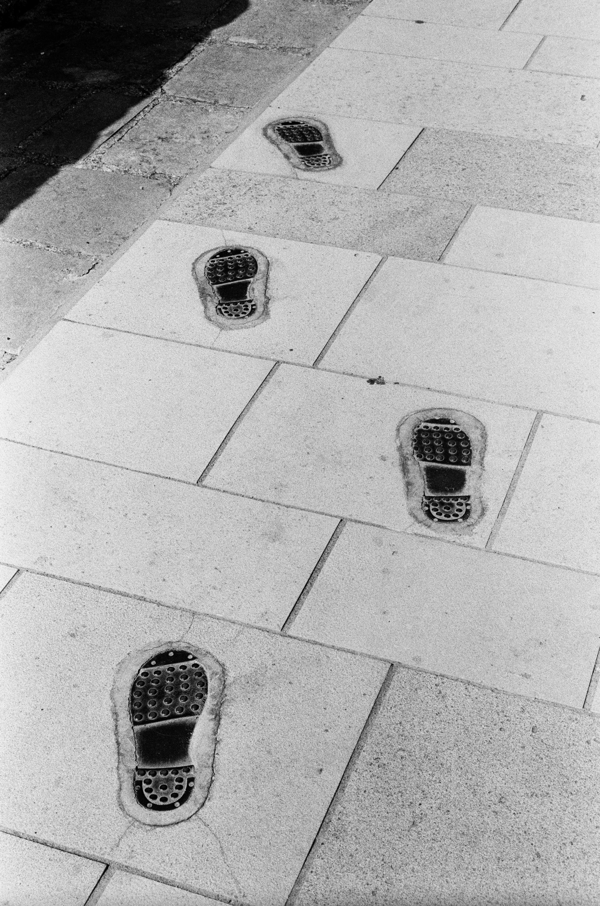 Four boot prints embedded in a light stone paved walkway