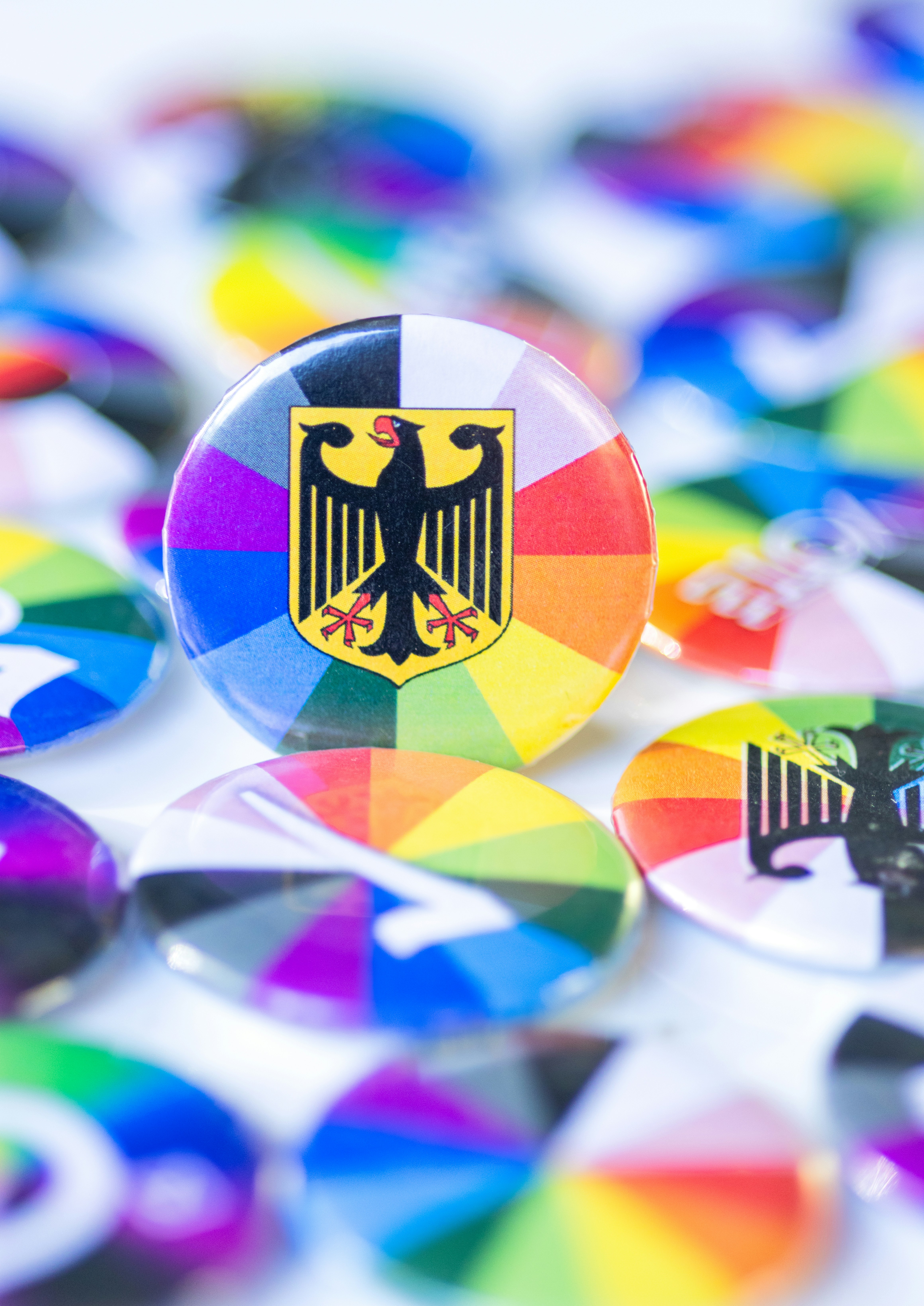 A circular pin featuring the German eagle emblem over a vibrant rainbow color wheel