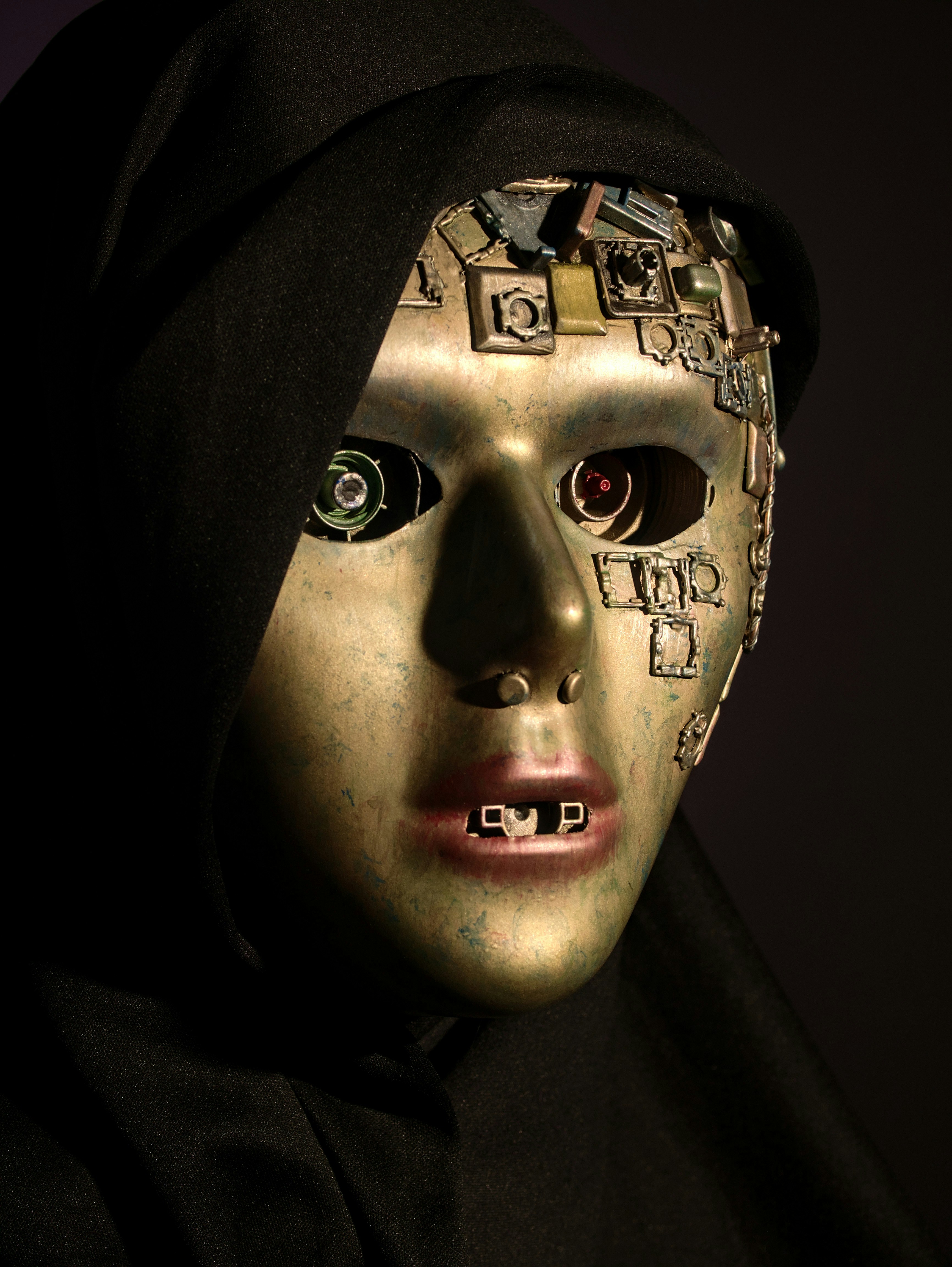 Una maschera cyborg metallica con componenti meccanici per gli occhi e circuiti su uno sfondo nero
