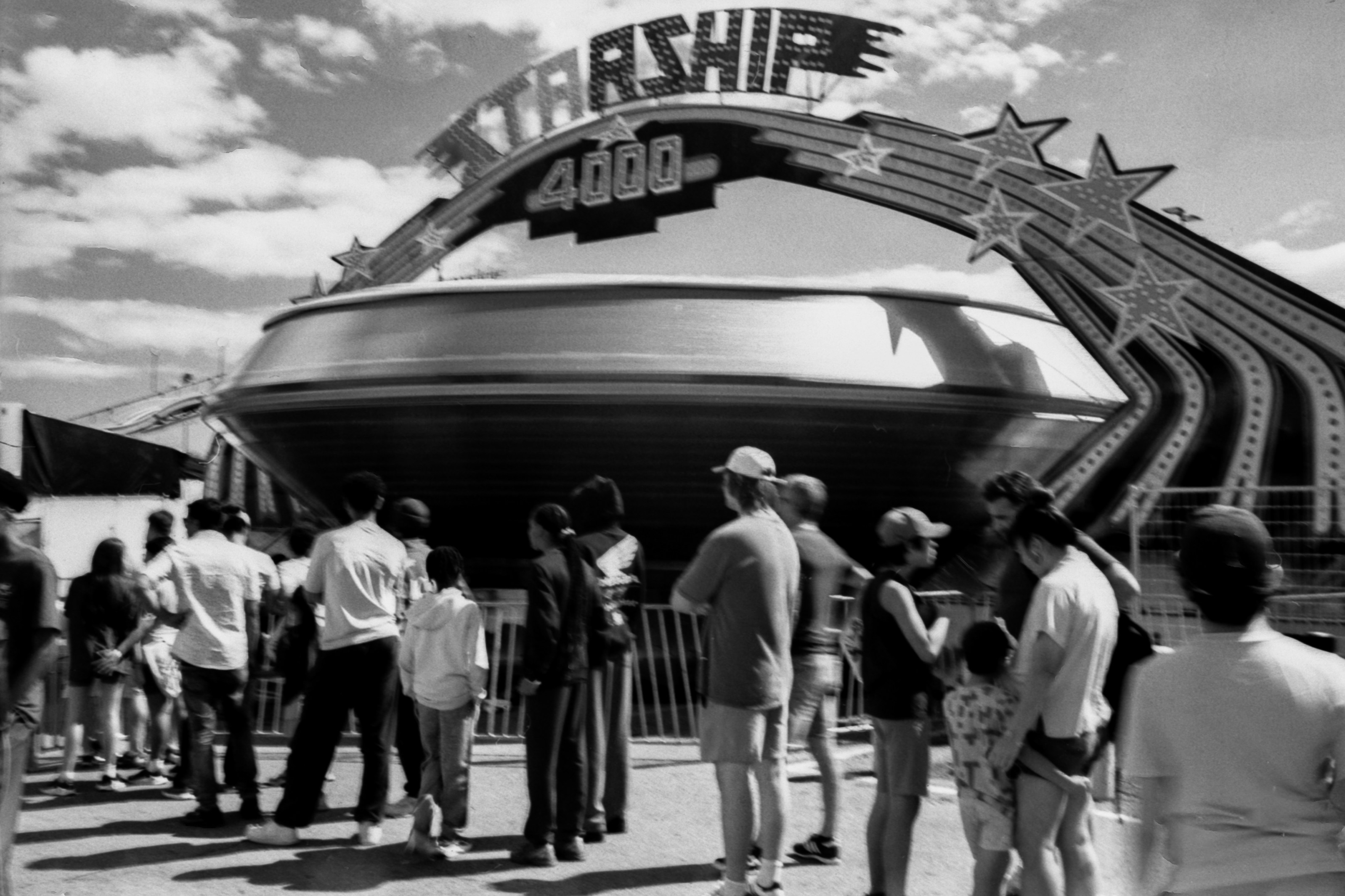 A group of people waiting in line for the Starship 4000 carnival ride